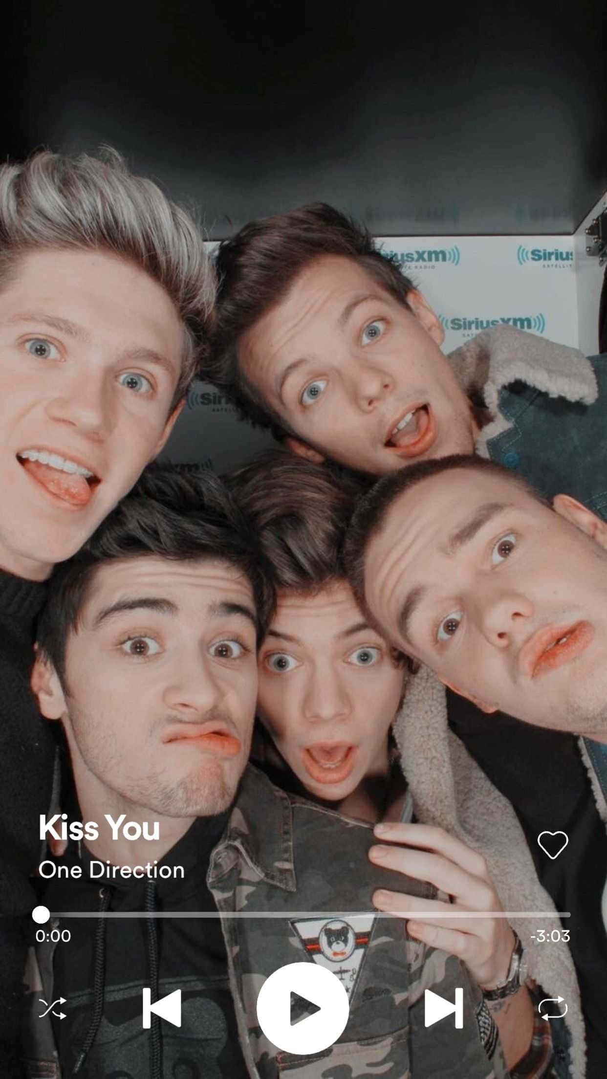 《Kiss You》One Direction iPhone 壁紙 — 五個年輕男子誇張地做鬼臉擠在一起自拍，上面覆蓋著One Direction的Kiss You音樂播放器界面。