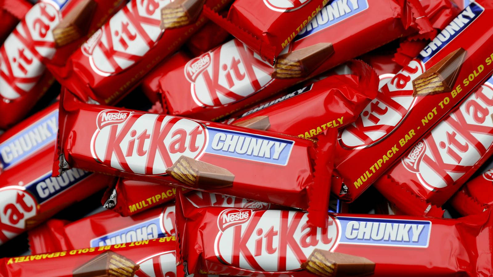 Kit Kat Chunky 壁紙 — 一堆充滿活力的紅色包裝KitKat Chunky朱古力條，可見牛軋糖和朱古力碎片。