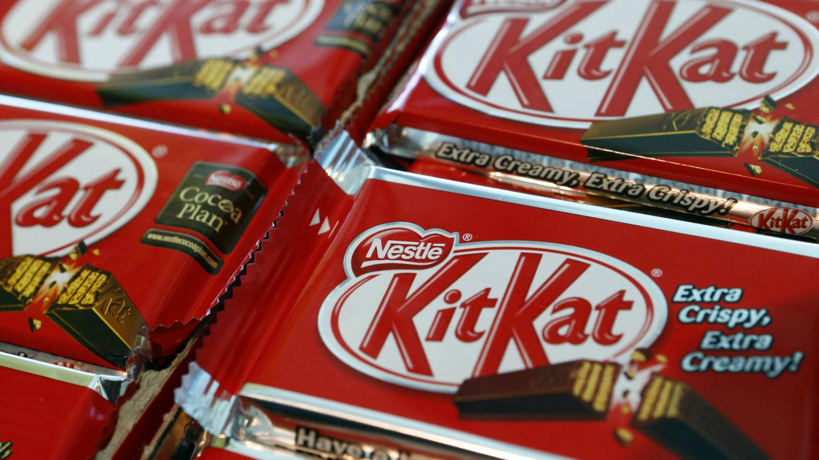 Kit Kat 巧克力 壁紙 — 紅色KitKat朱古力條特寫，帶有'Extra Crispy Extra Creamy'文字和金色箔紙包裝。