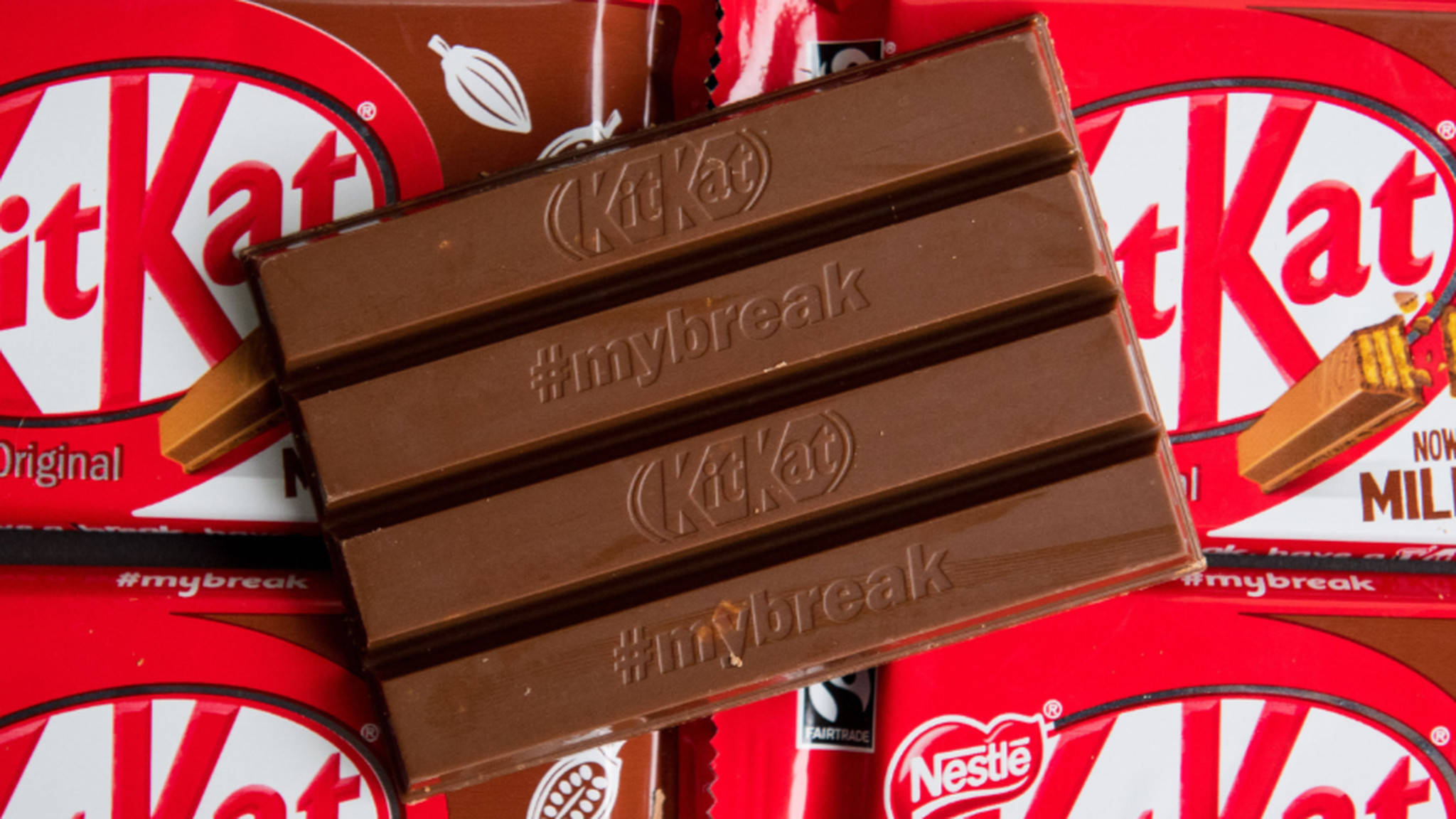 Kit Kat「我的休息時間已解開」 壁紙 — KitKat 朱古力棒的近距離特寫，其分段上印有 #mybreak，放在紅色 KitKat 包裝紙上。