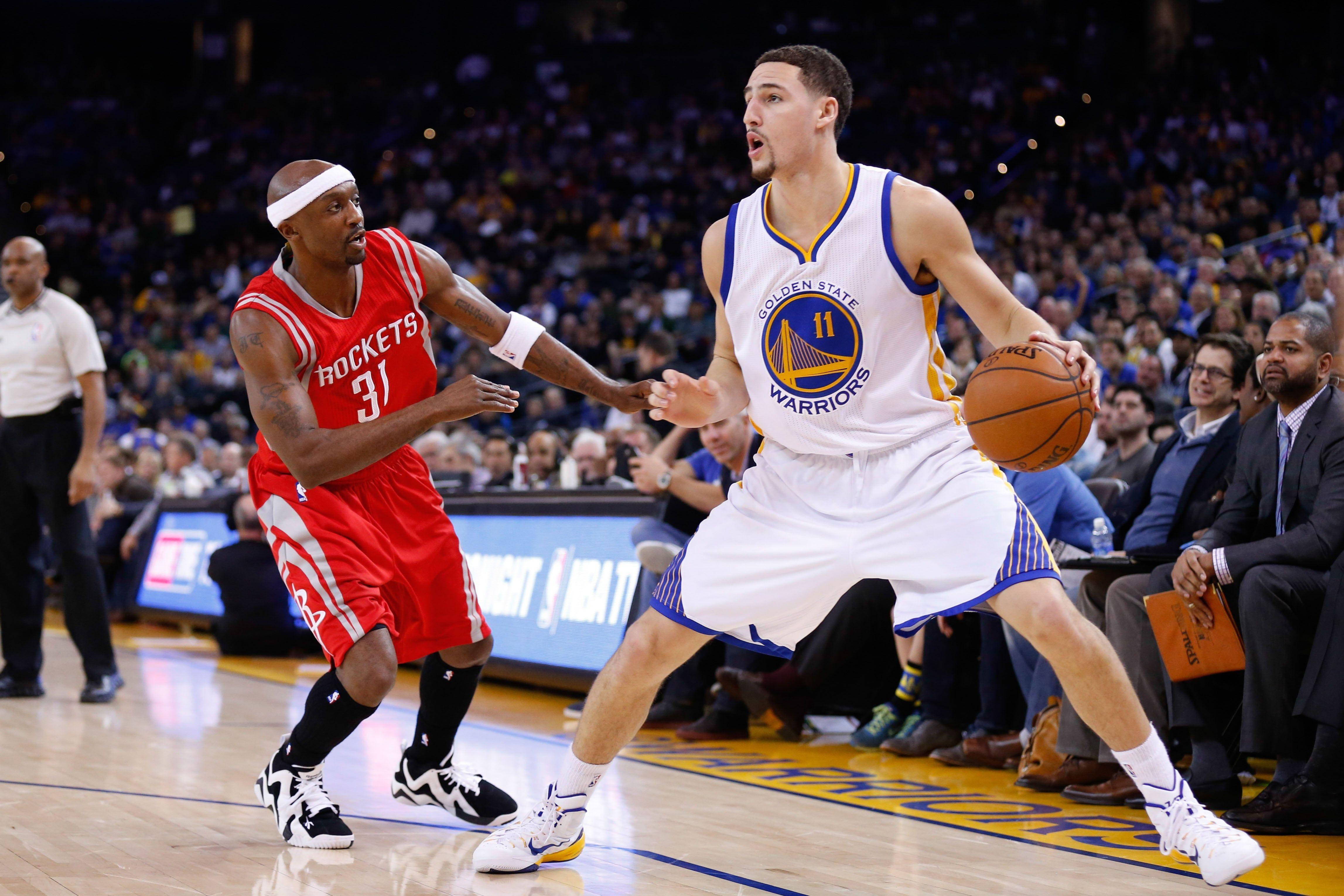 Klay Thompson 後撤步 壁紙 — 金州勇士隊球員在滿座的NBA比賽中運球，同時被侯斯頓火箭隊球員緊密防守。