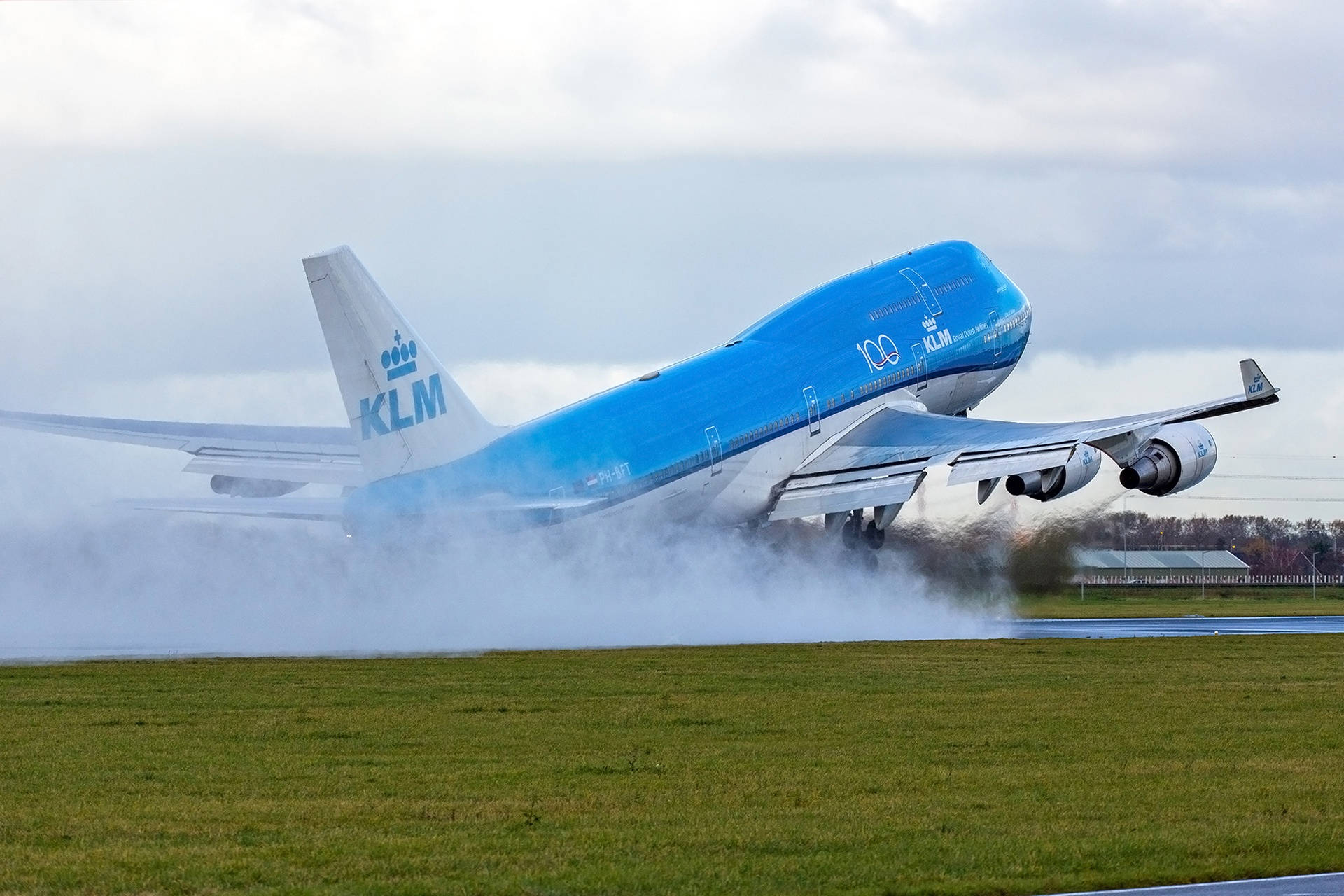 KLM波音747在陰天起飛時激起水霧。