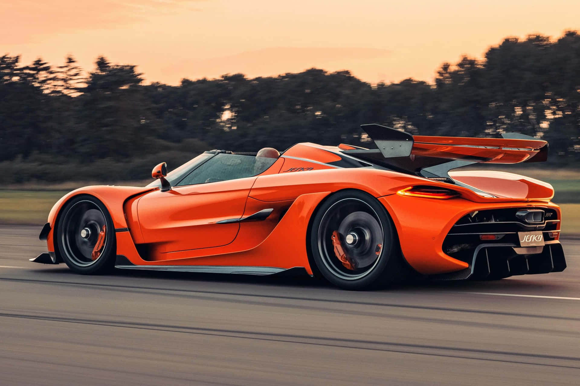 橙色Koenigsegg Jesko在日落時分的道路上飛馳