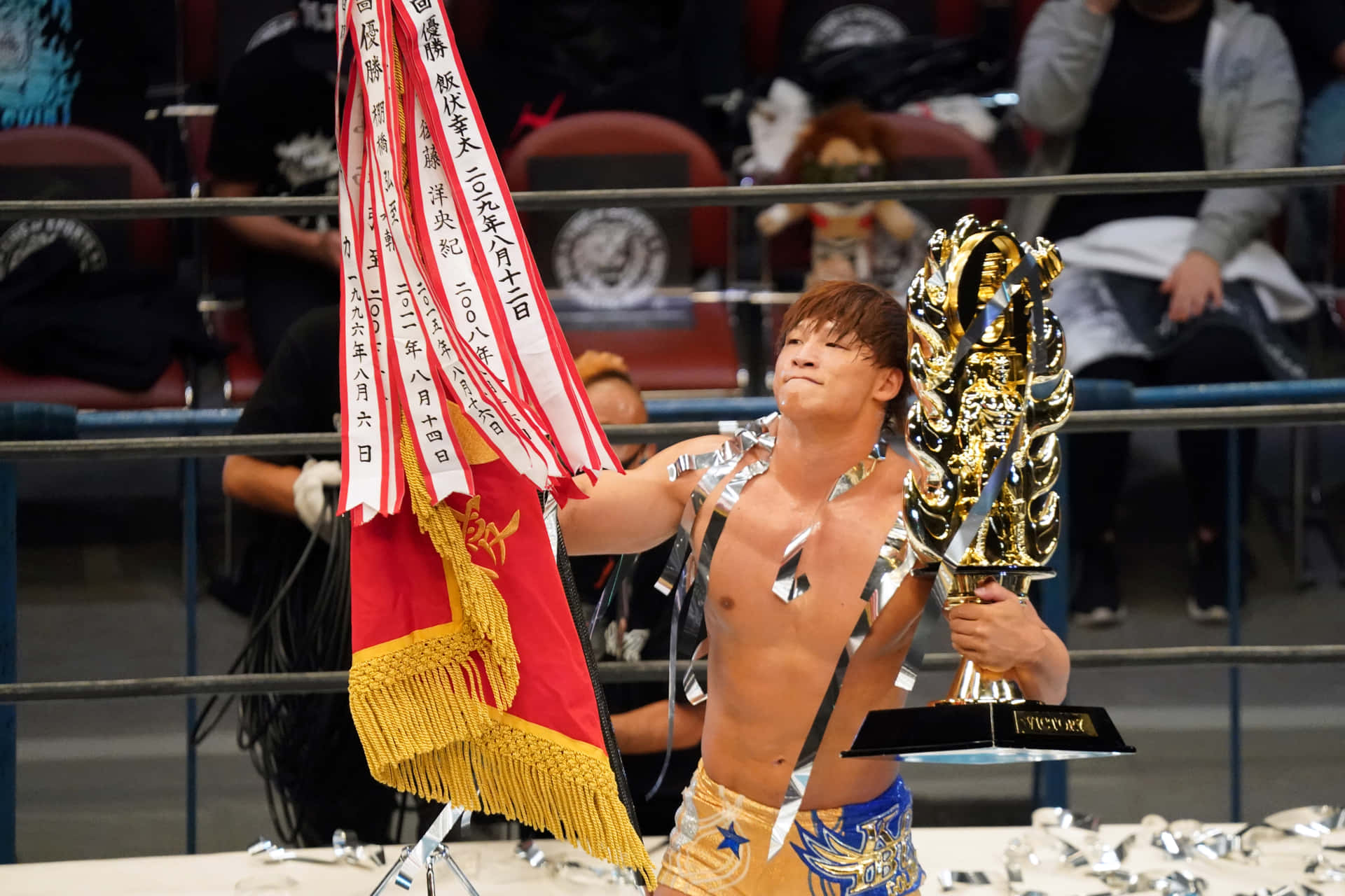 摔角手在擂台上高舉獎盃和橫幅慶祝勝利