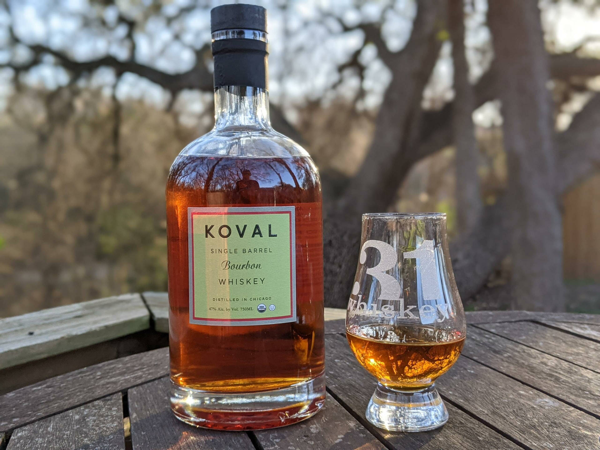 Koval 波本威士忌酒瓶和酒杯在戶外木桌上