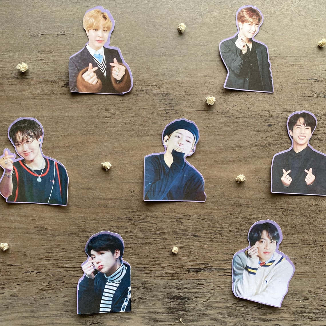 KPOP BTS 指心貼紙 壁紙 — 七張K-pop偶像的剪裁照片用小裝飾釘固定在質樸的木質表面上。