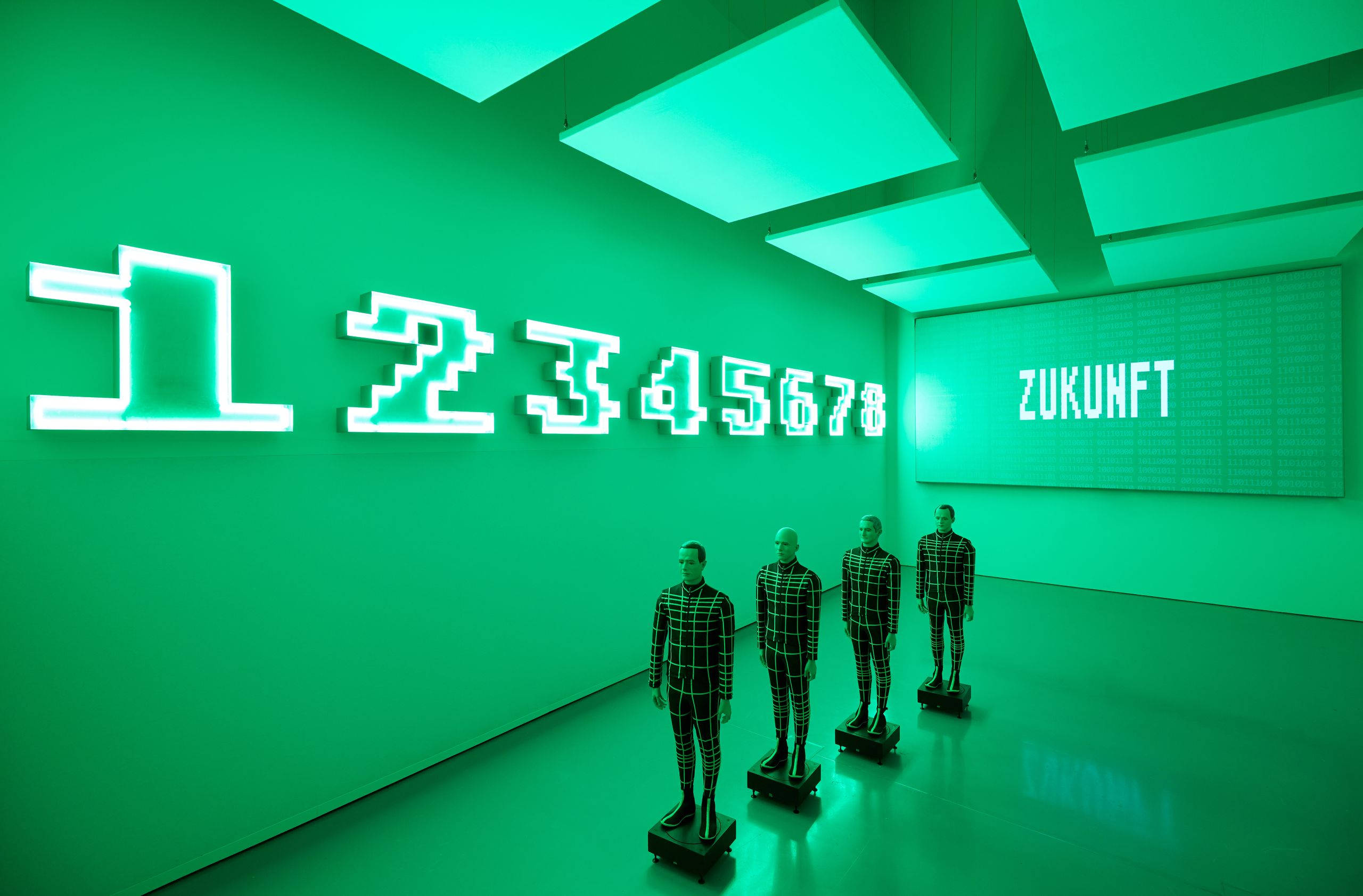 Kraftwerk「Zukunft」綠色背景克隆影像 壁紙 — 四個穿著格紋圖案的人體模型站在一個霓虹綠色的畫廊中，牆上有發光的數字和單詞ZUKUNFT。
