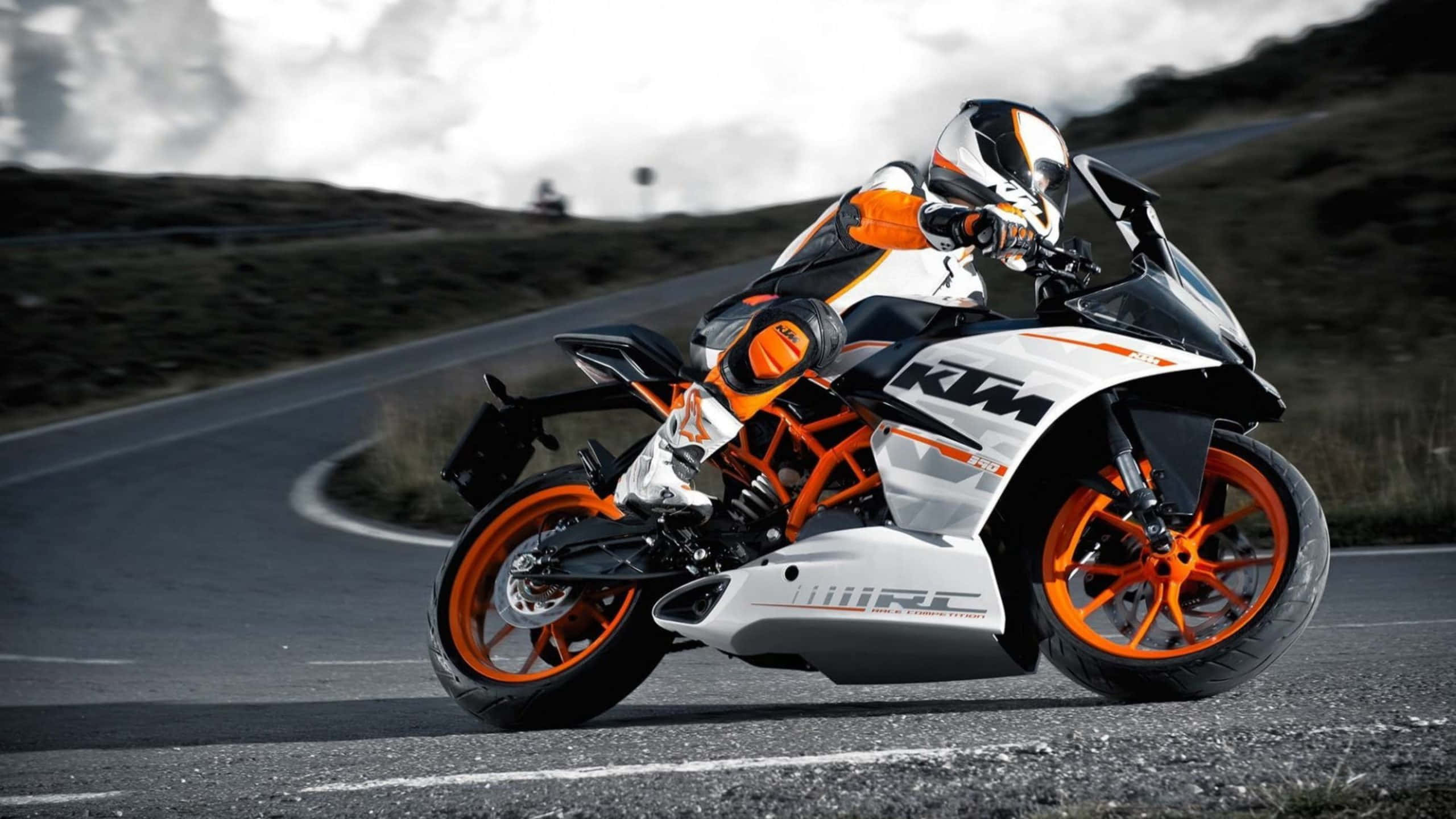KTM 390 圖片 壁紙 — 一名騎手在蜿蜒的山路上，騎著白色和橙色的KTM運動電單車，傾身進入一個急彎。