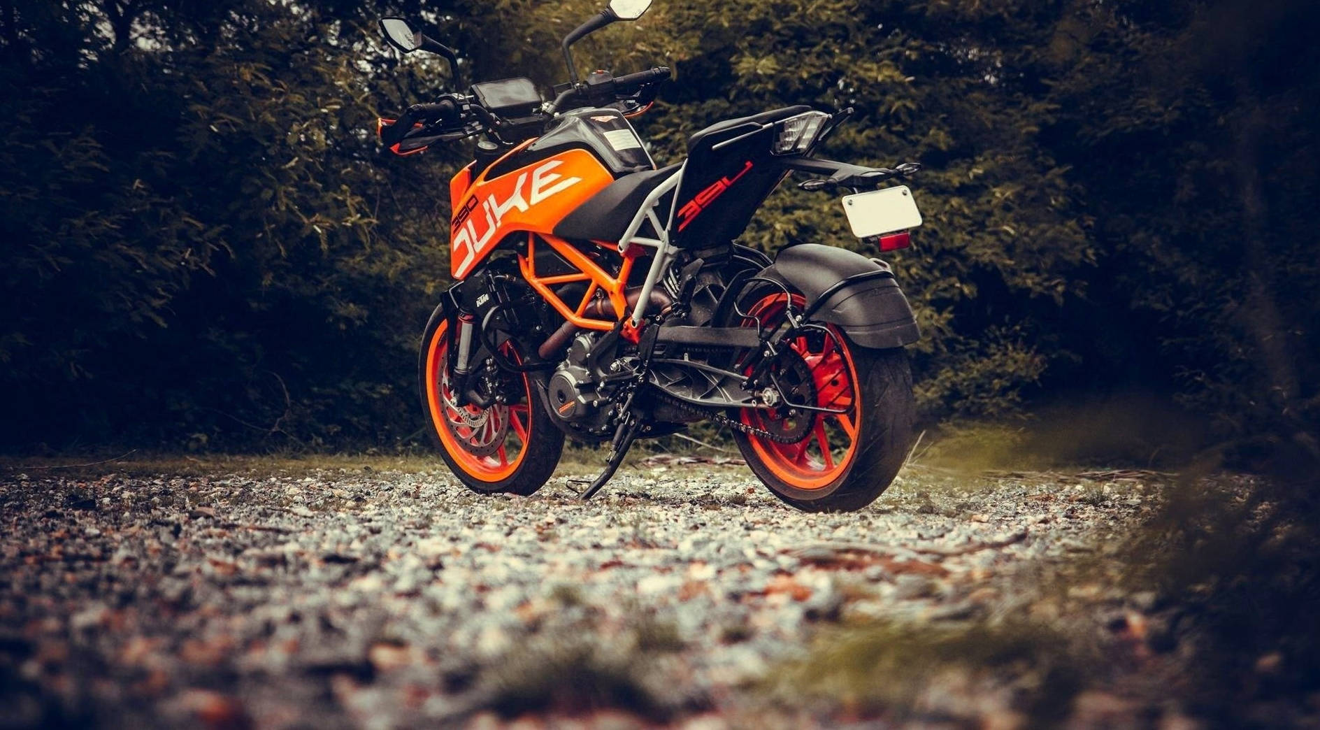橙色和黑色KTM Duke電單車停泊在森林中的碎石上。
