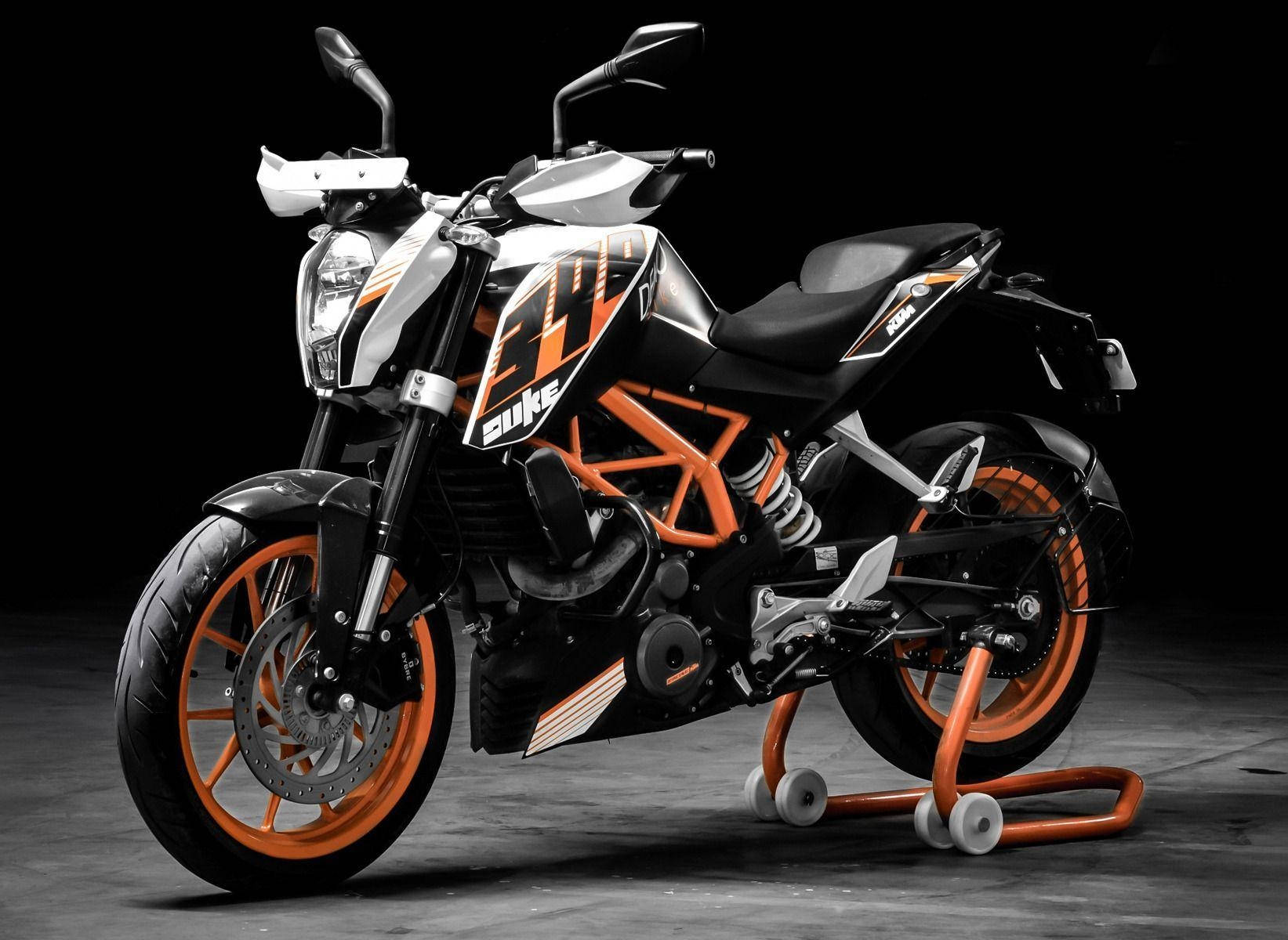 深色工作室中支架上的黑色和橙色KTM Duke電單車。