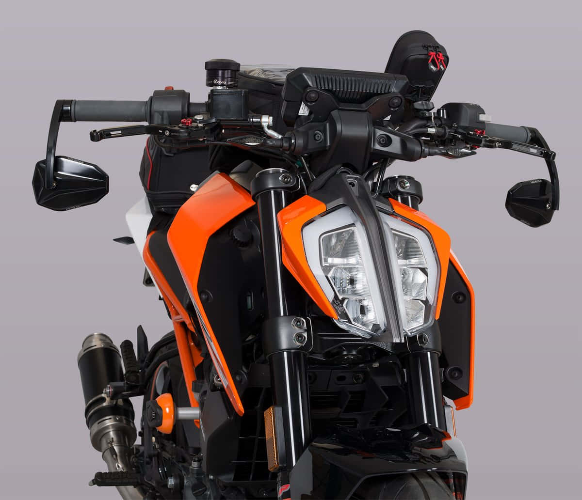 經典KTM Duke 壁紙 — 近距離拍攝一輛時尚的橙色和黑色運動電單車，配備鋒利頭燈和鍍鉻排氣管，背景為中性灰色。