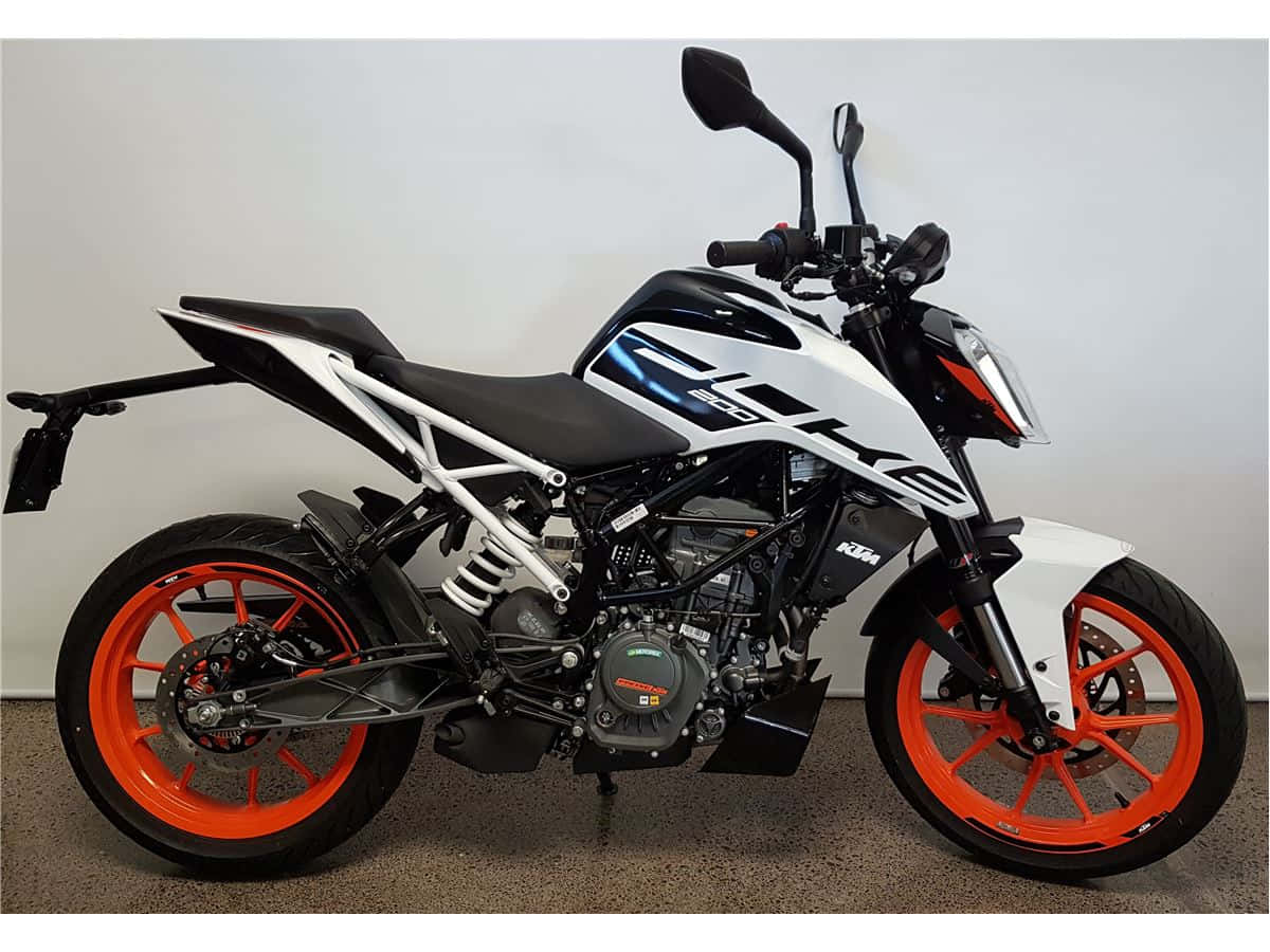 KTM Duke TDI 125摩托車圖片 壁紙 — 一台時尚的黑白KTM電單車，配以充滿活力的橙色車輪，在簡約的攝影棚環境中屹立。