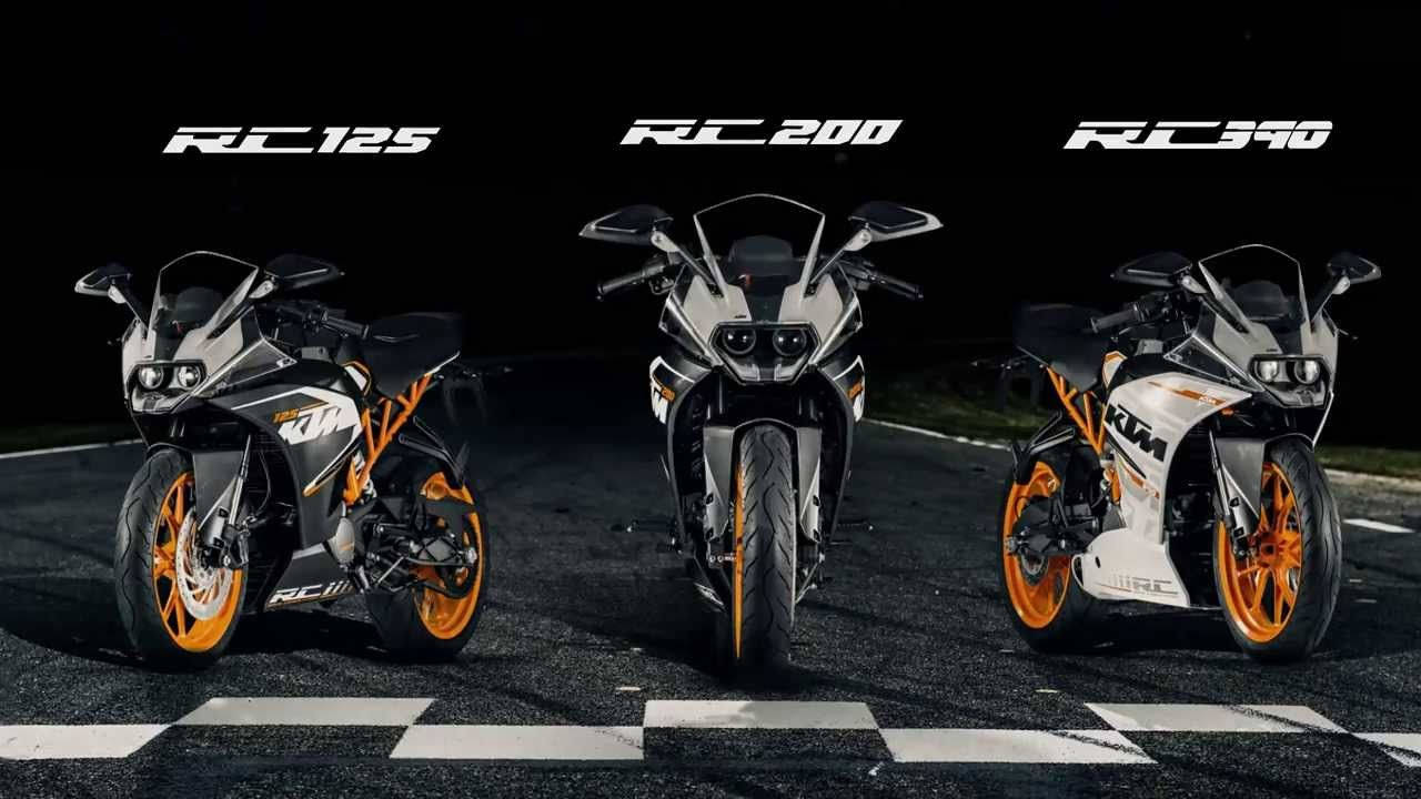 KTM RC 200 展示 壁紙 — 三輛白色和橙色的KTM RC運動電單車在夜間戲劇性燈光下，蓄勢待發地停在方格賽車道上。
