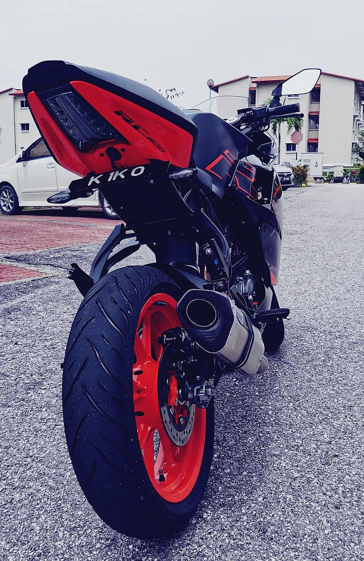 KTM RC 200尾管 壁紙 — 一架搶眼的紅黑色運動電單車停在瀝青路上，背景是住宅建築。