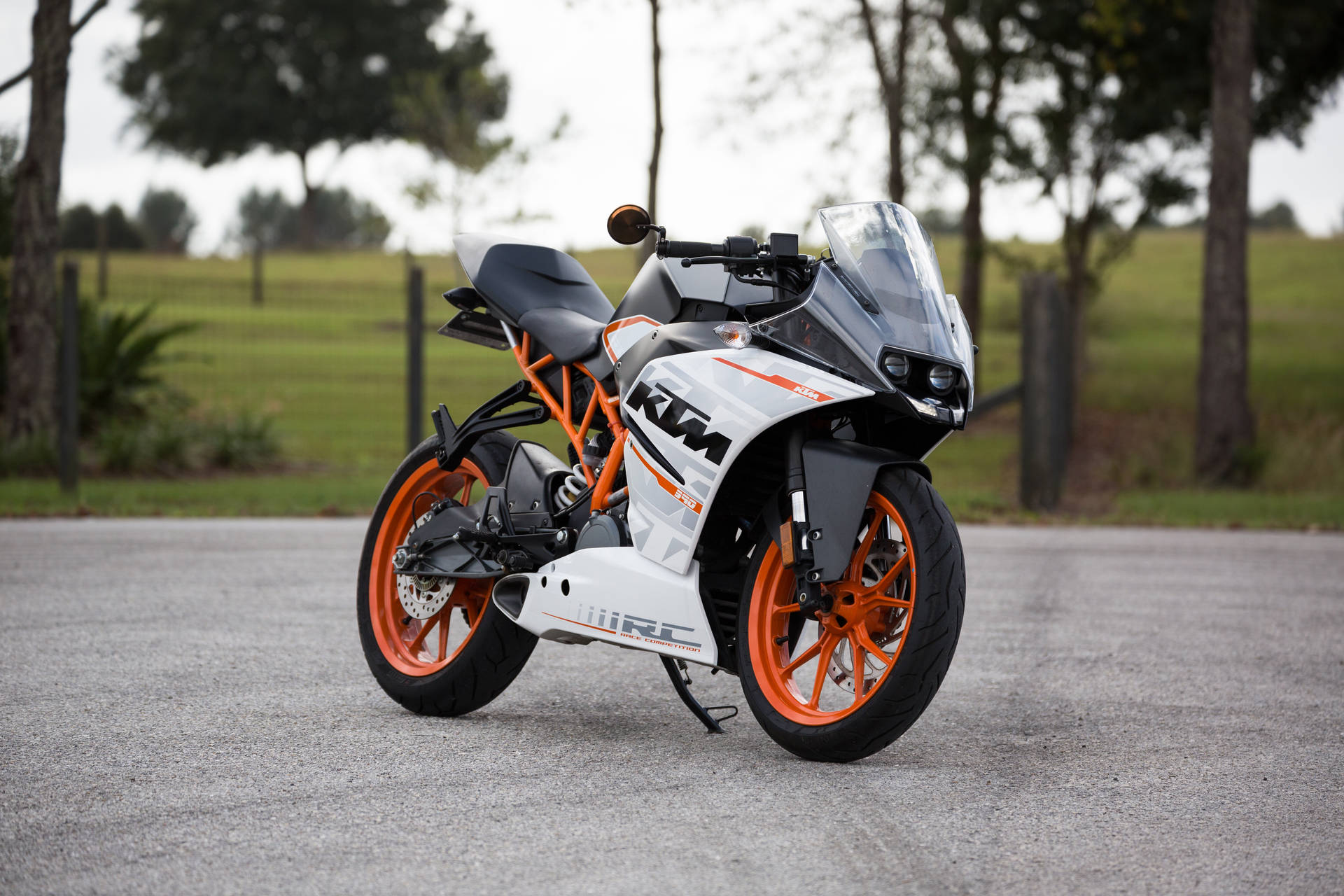 一輛白色和橙色的KTM RC運動電單車停在鋪砌的道路上。