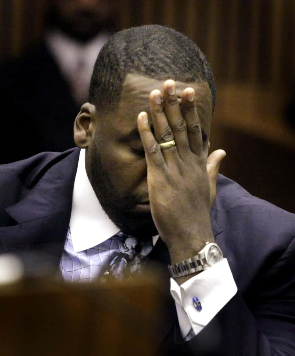 Kwame Kilpatrick出席記者會 壁紙 — 一名身穿西裝的男子在法庭上用手遮住臉。