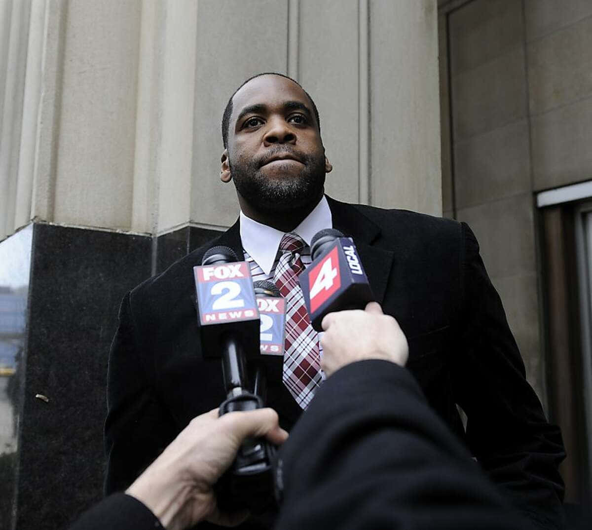 Kwame Kilpatrick專業肖像照 壁紙 — 一名身穿西裝打領帶的男子站在建築物外，記者們將麥克風遞向他。