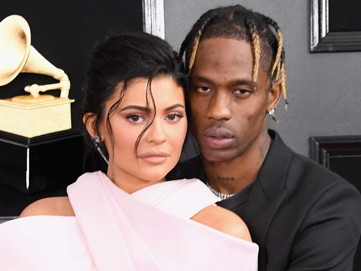 Travis Scott 壁紙 — Kylie Jenner 和 Travis Scott 在葛萊美獎活動中緊密擺姿勢，背景有金色獎盃。