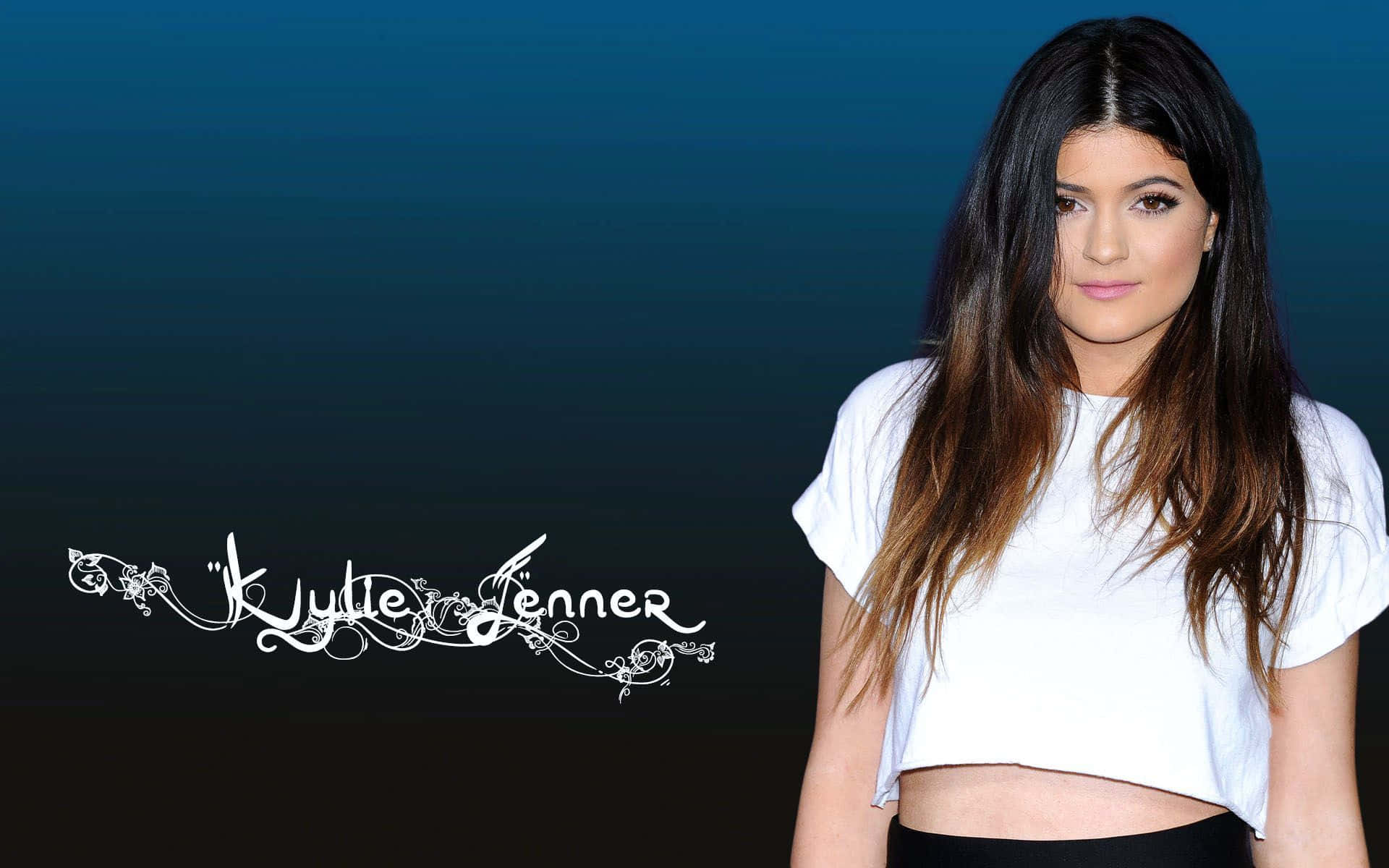 Kylie Jenner 桌布 壁紙 — Kylie Jenner 穿著白色短上衣，在漸變藍色背景前擺姿勢，她的名字以華麗的白色字體呈現。