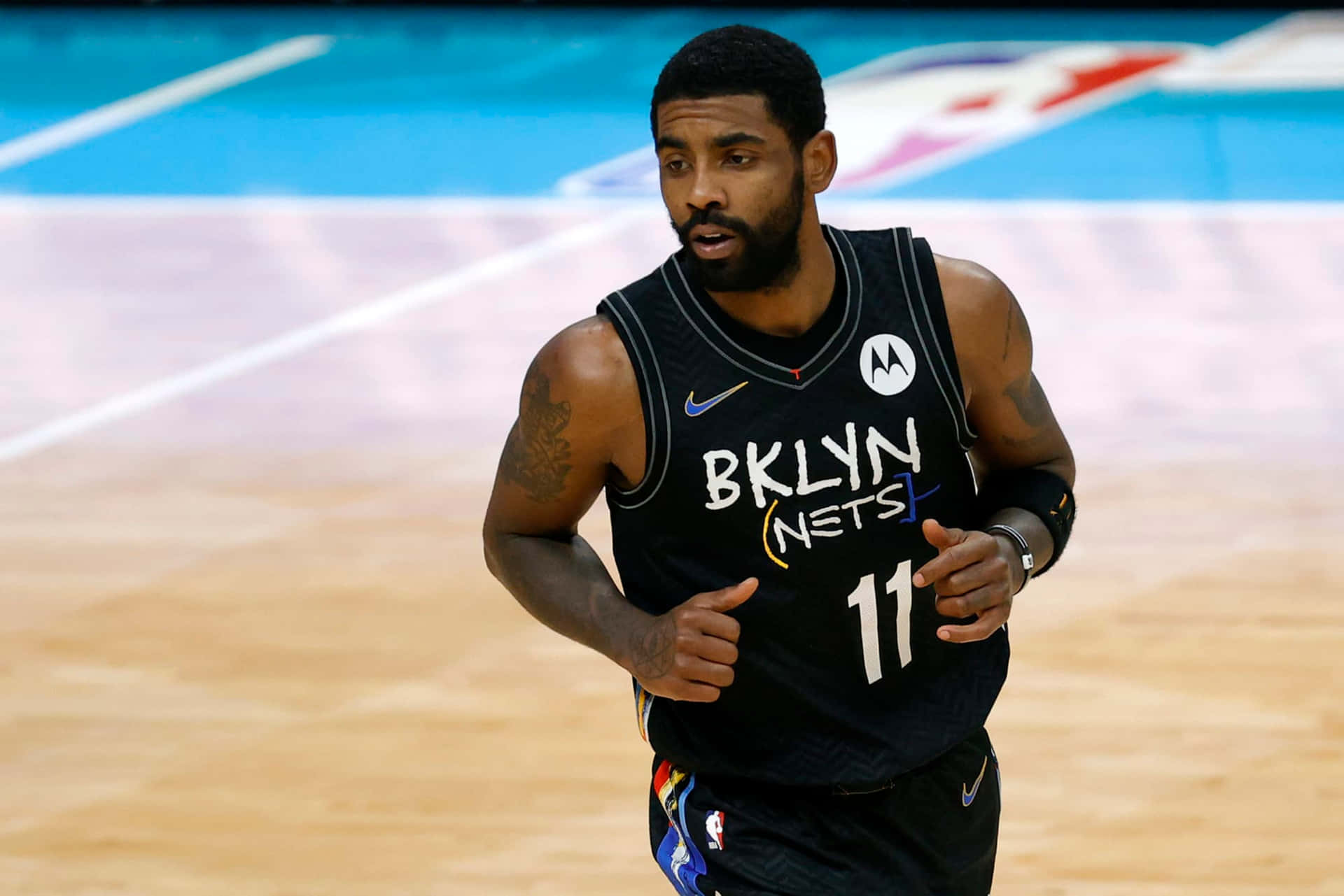 Kyrie Irving 網隊奔跑 壁紙 — 布魯克林籃網籃球運動員凱里·歐文穿著黑色球衣在比賽期間於硬木球場上奔跑。