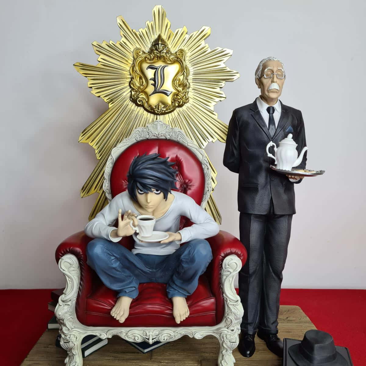 Death Note Watari 桌布 壁紙 — L 與青山的動漫人偶，坐在帶有金色 L 標誌和茶具的華麗紅色椅子上。