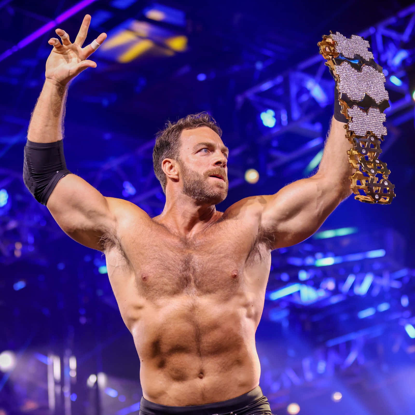 La Knight 獲得 WWE NXT Million Dollar Champion 壁紙 — 一位肌肉發達的摔角手在充滿活力的藍色舞台燈光下勝利地高舉閃閃發光的冠軍腰帶。