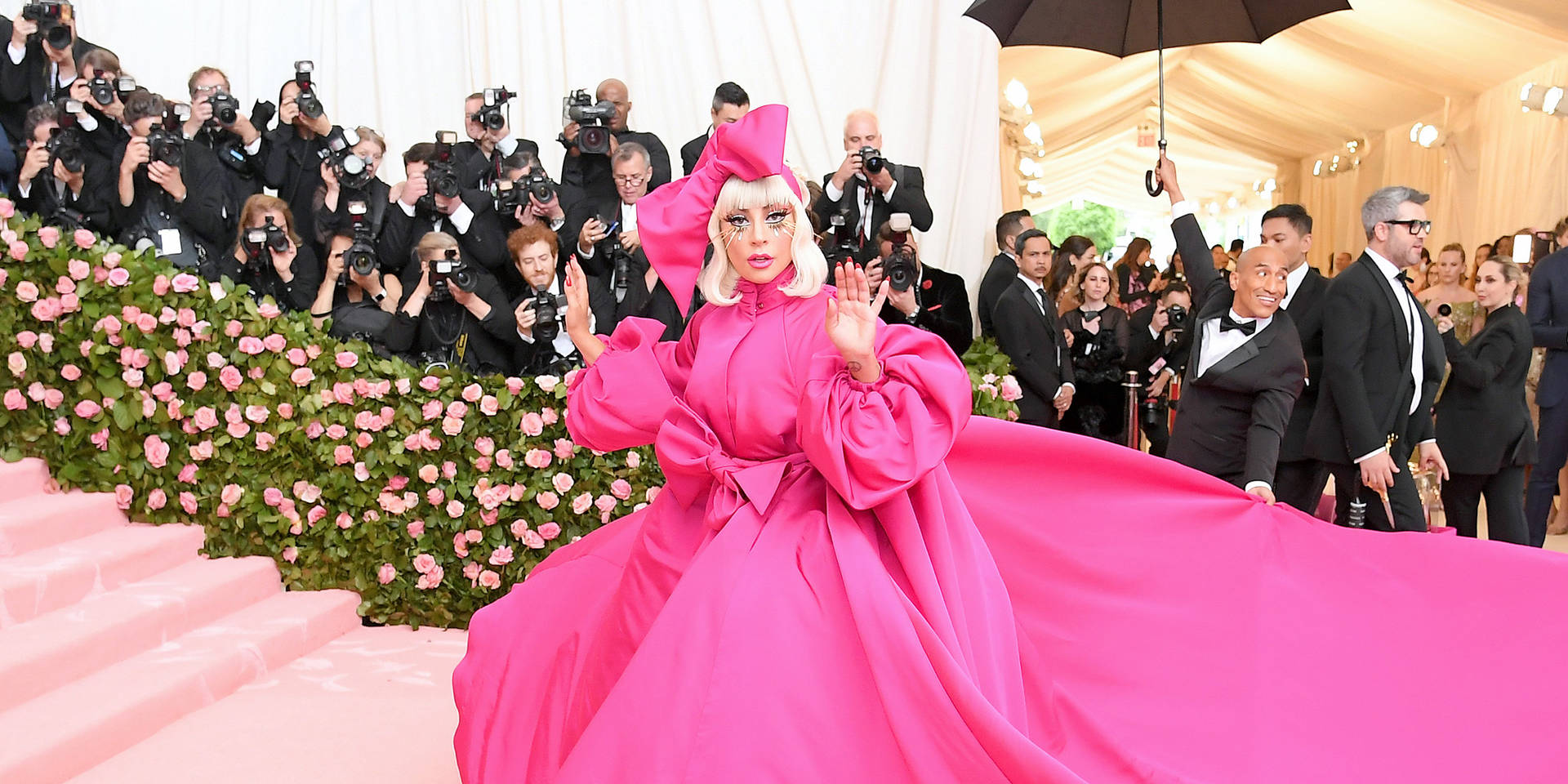 Lady Gaga 身穿粉紅色長袍在 Met Gala 紅地毯活動上揮手。