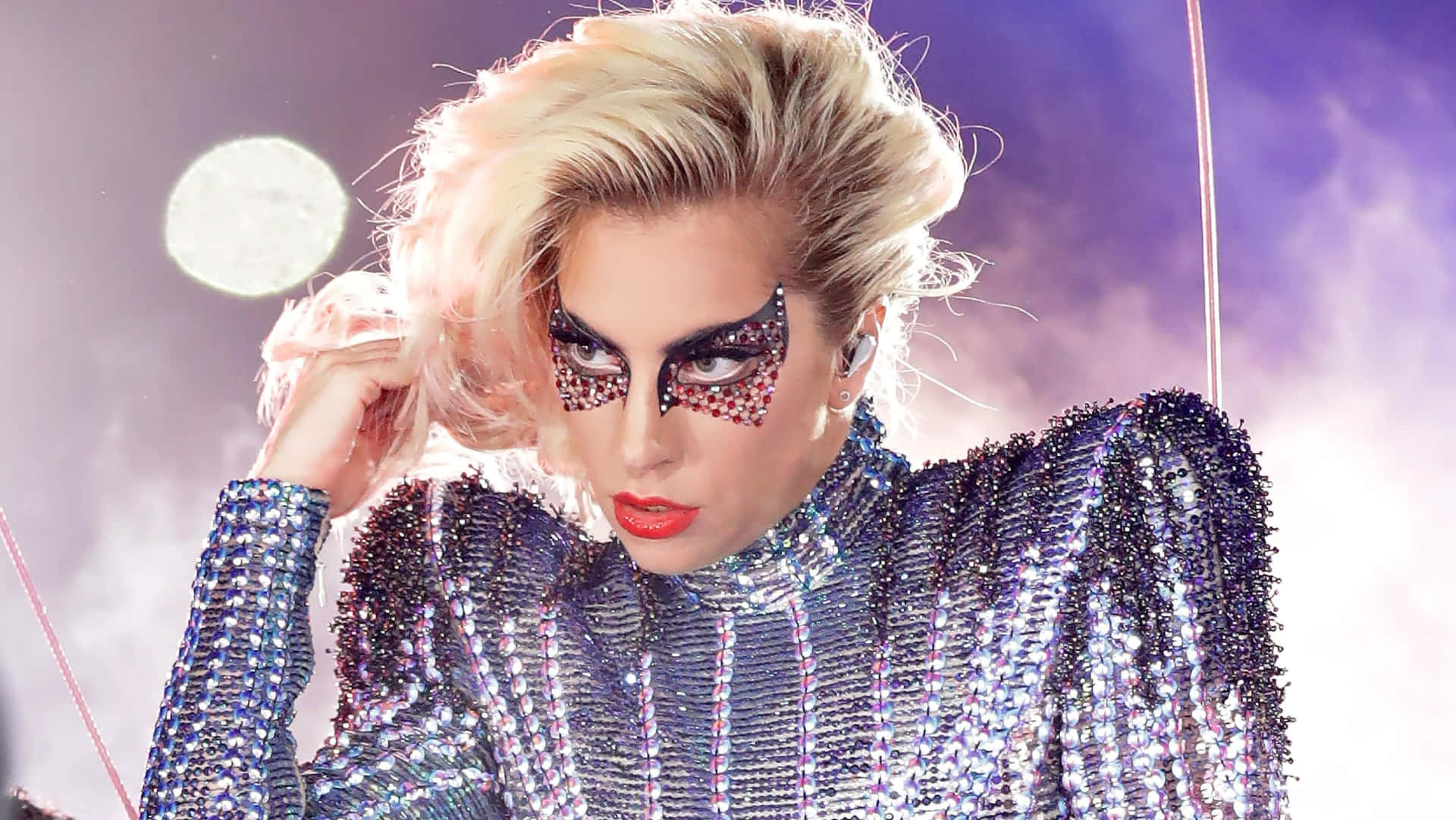 Lady Gaga 身穿閃亮銀色服裝，在舞台上展現閃爍眼妝。