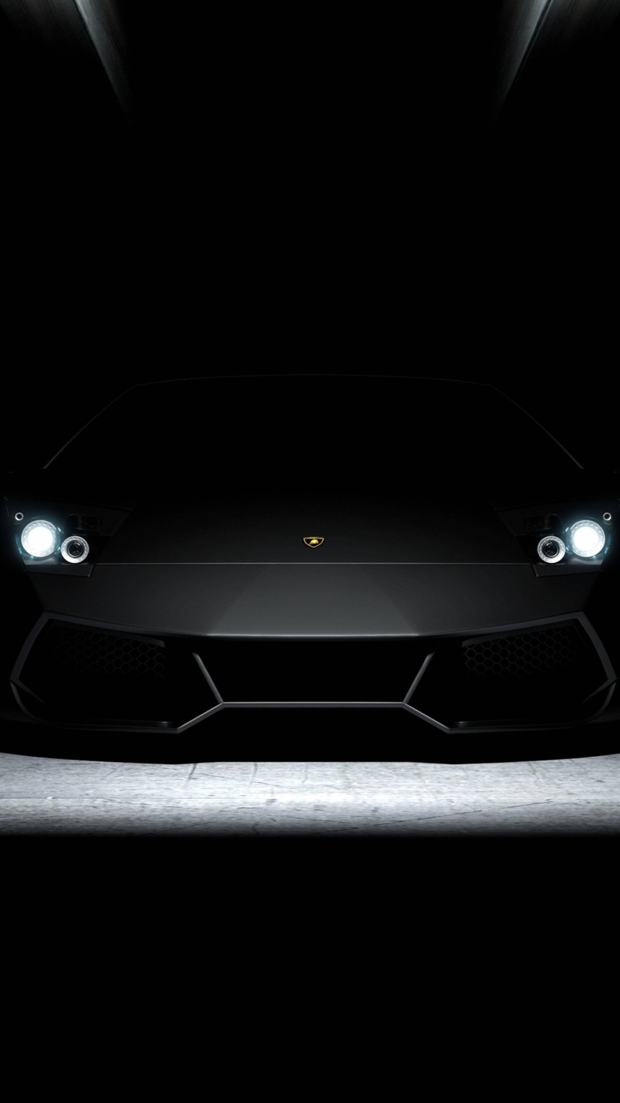 Lamborghini 4K 超高清深色手機壁紙 壁紙 — 一輛時尚黑色林寶堅尼的前視圖，在黑暗背景下被發光的車頭燈照亮。