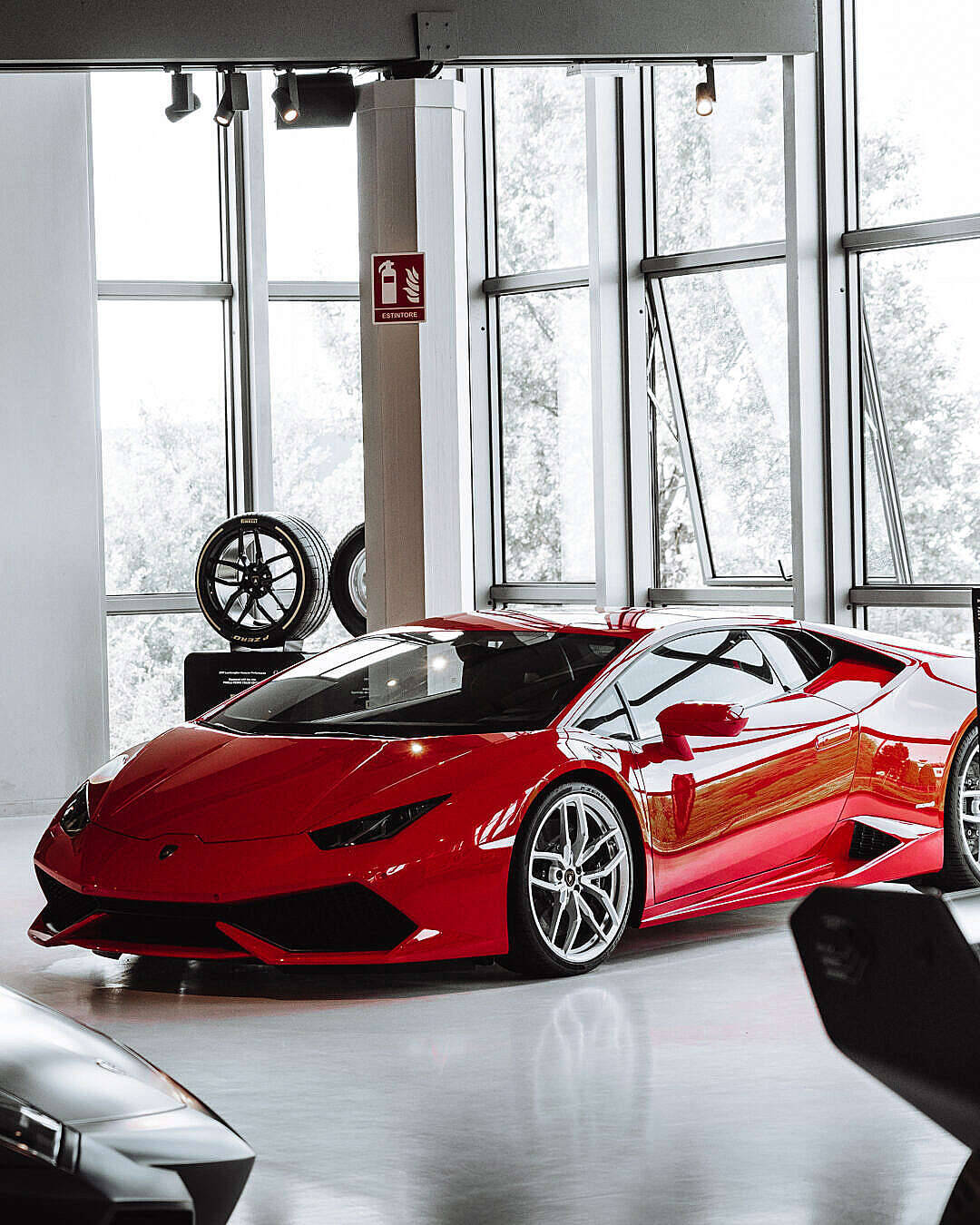 紅色Lamborghini Huracan - 奢華與力量的化身 壁紙 — 一輛光澤的紅色林寶堅尼跑車在明亮燈光下，於一個簡約白色、設有大窗戶的陳列室中閃耀。