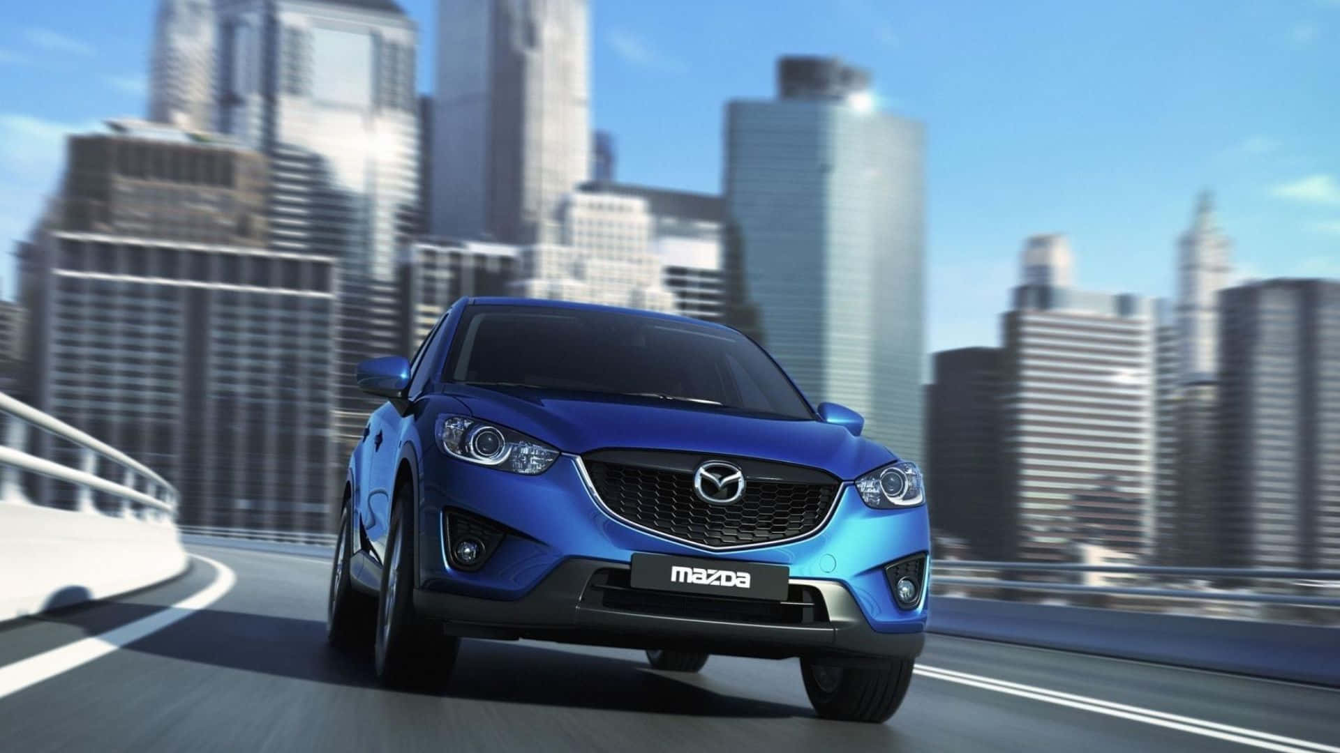 Mazda Cx-5 桌布 壁紙 — 一輛充滿活力的藍色Mazda SUV在彎曲的高速公路上疾馳，背景是現代城市天際線，天空湛藍。