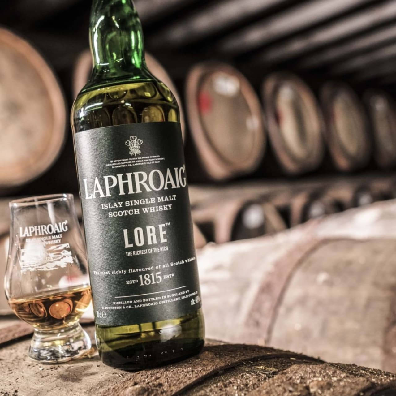 蒸餾廠木桶上嘅Laphroaig Lore威士忌酒瓶同品酒杯。