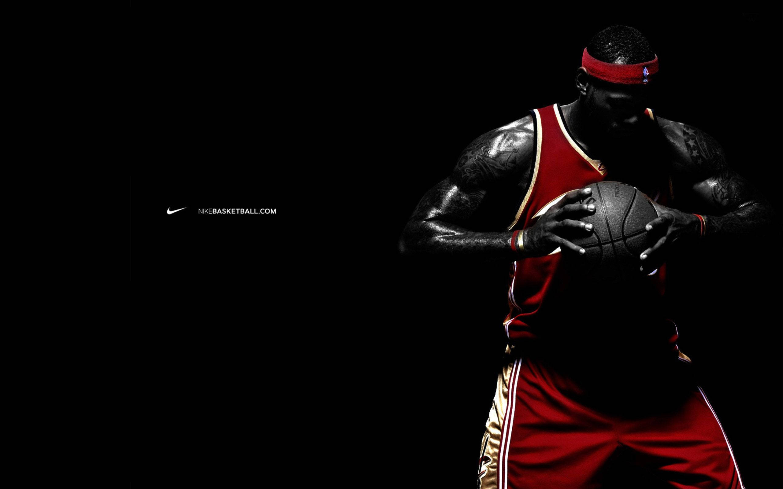好萊塢之王 LeBron James 壁紙 — 一名身穿紅色球衣的籃球運動員在戲劇性燈光的黑色背景下抓住一個球。