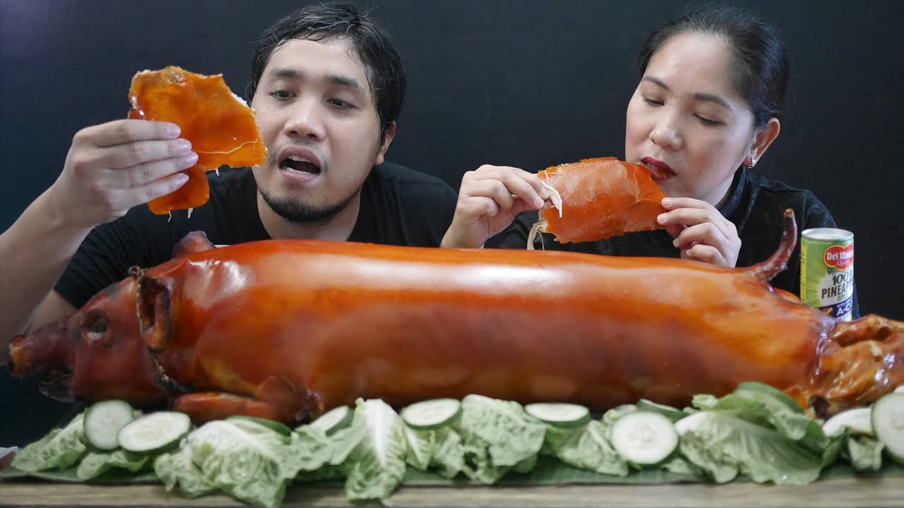 情侶享受脆皮烤豬肉配青瓜和生菜。