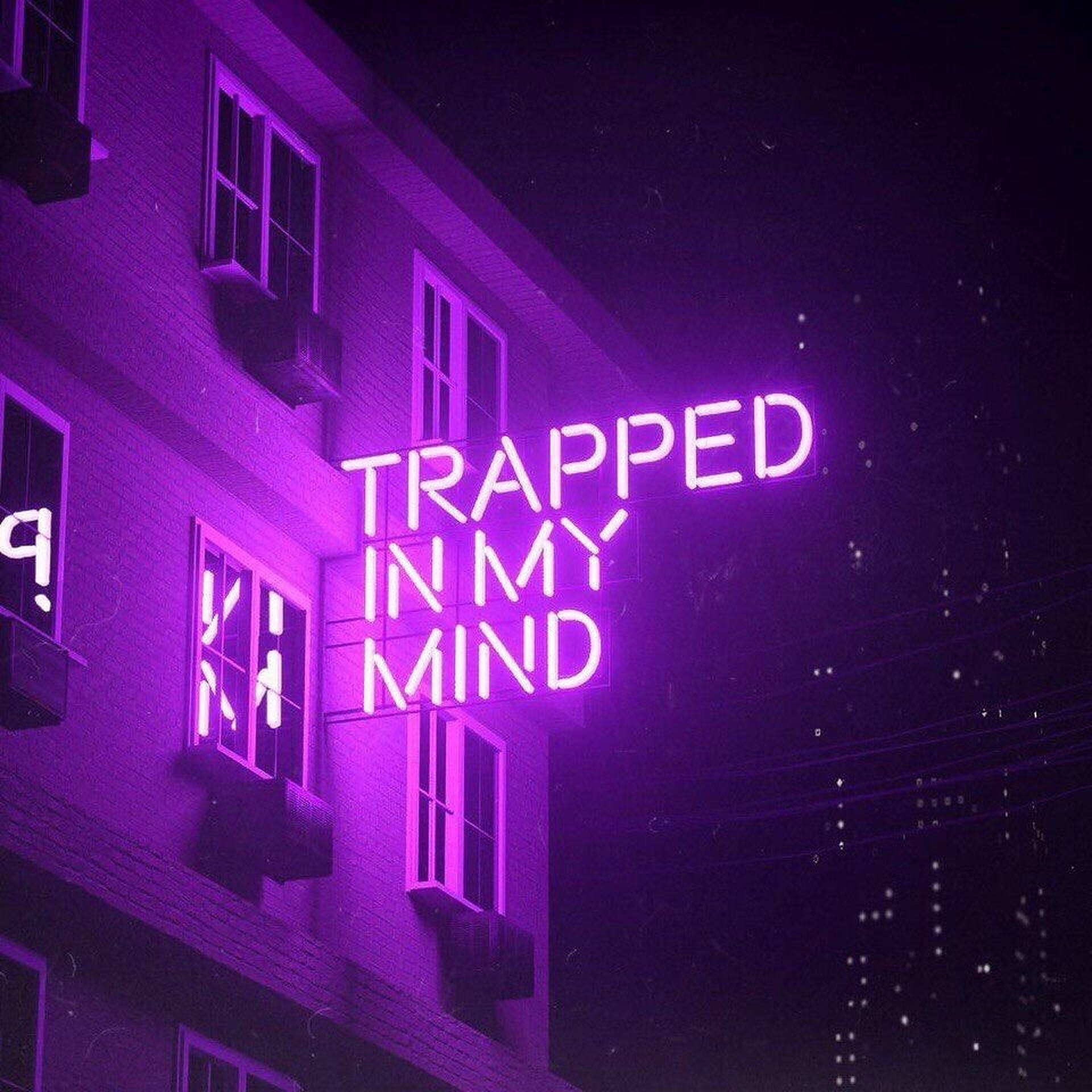 夜晚磚牆上寫著 trapped in my mind 的霓虹燈牌。
