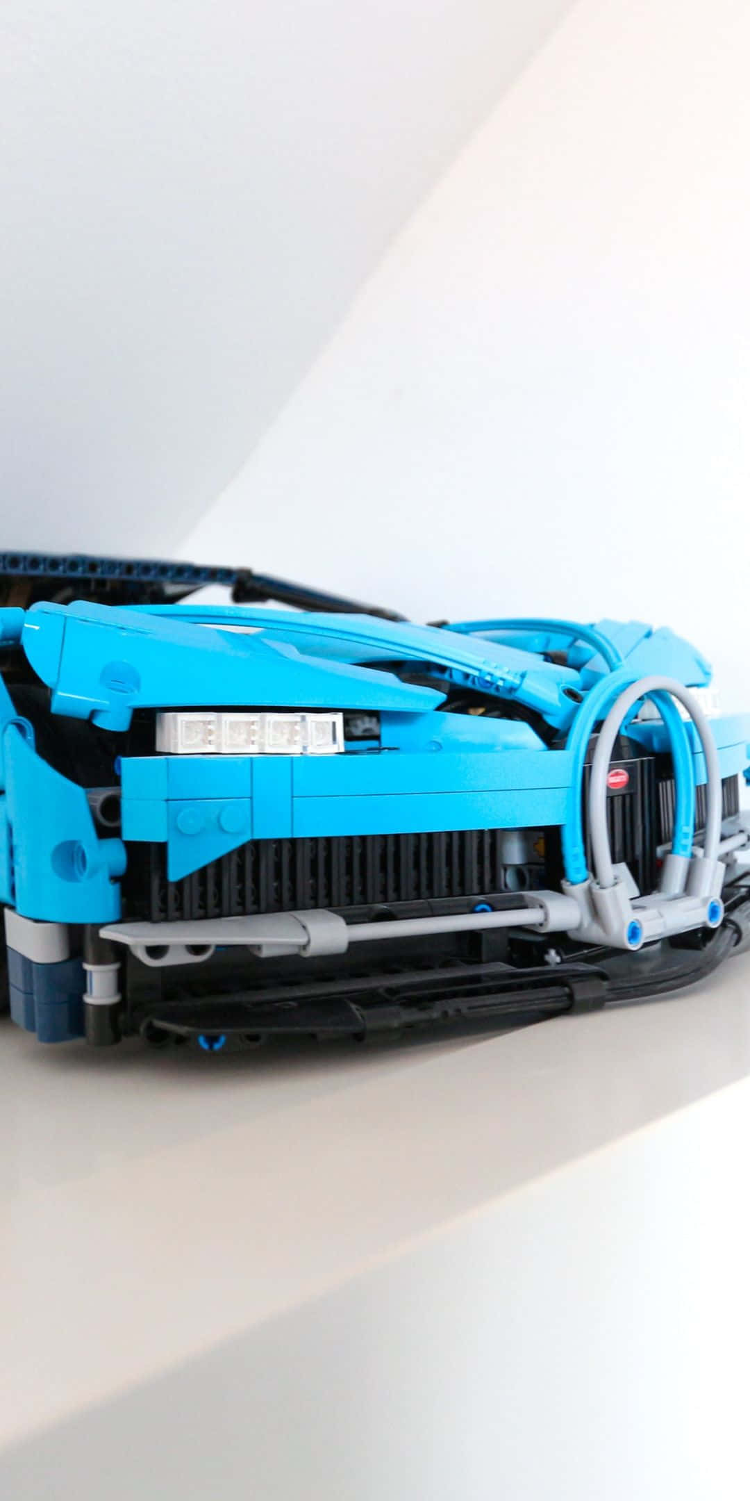 LEGO Technic 奇龍 Pixel 3 Bugatti 背景 壁紙 — 藍色LEGO Technic跑車模型的近距離特寫，在簡約白色背景上展示複雜的機械細節。