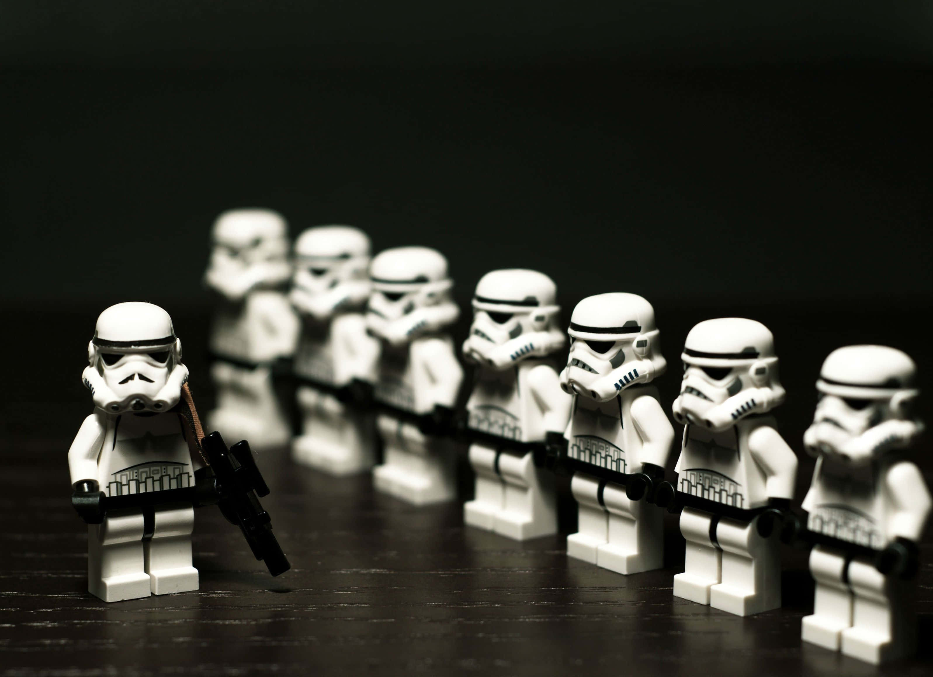 LEGO積木的無限可能 壁紙 — 一排LEGO風暴兵在黑暗背景前清晰對焦，景深較淺。