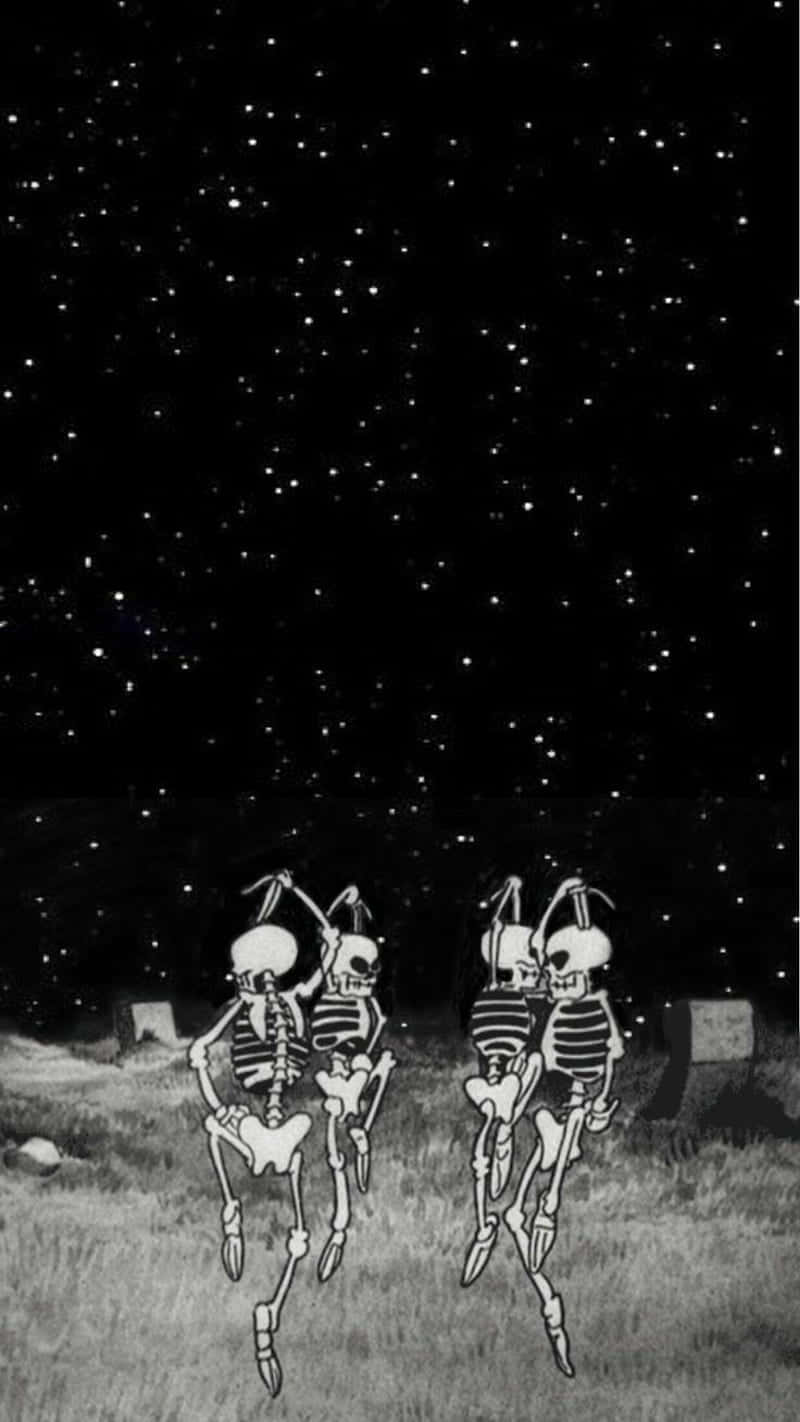  壁紙 — 兩個跳舞的骷髏在星空下的草地上與墓碑一起歡快地旋轉。