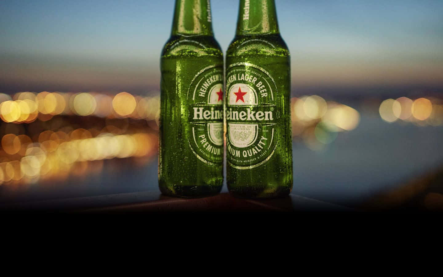 兩瓶冰凍的喜力啤酒放在欄杆上，俯瞰暮色中的城市。