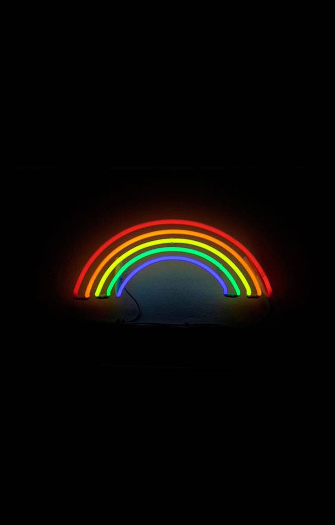 彩虹霓虹裝飾 LGBT 手機壁紙 壁紙 — 發光的霓虹彩虹在漆黑的背景下明亮地拱起，將柔和的有色光投射到下方的表面上。