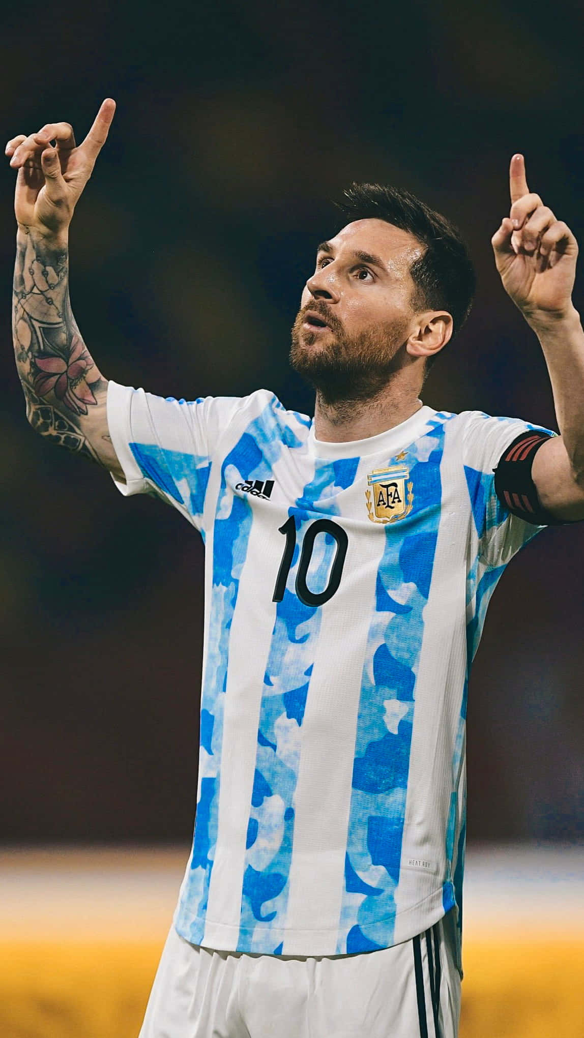 Messi 2022 桌布 壁紙 — 利昂內爾·美斯身穿阿根廷藍白間條球衣，在夜間足球比賽中高舉雙食指慶祝勝利。