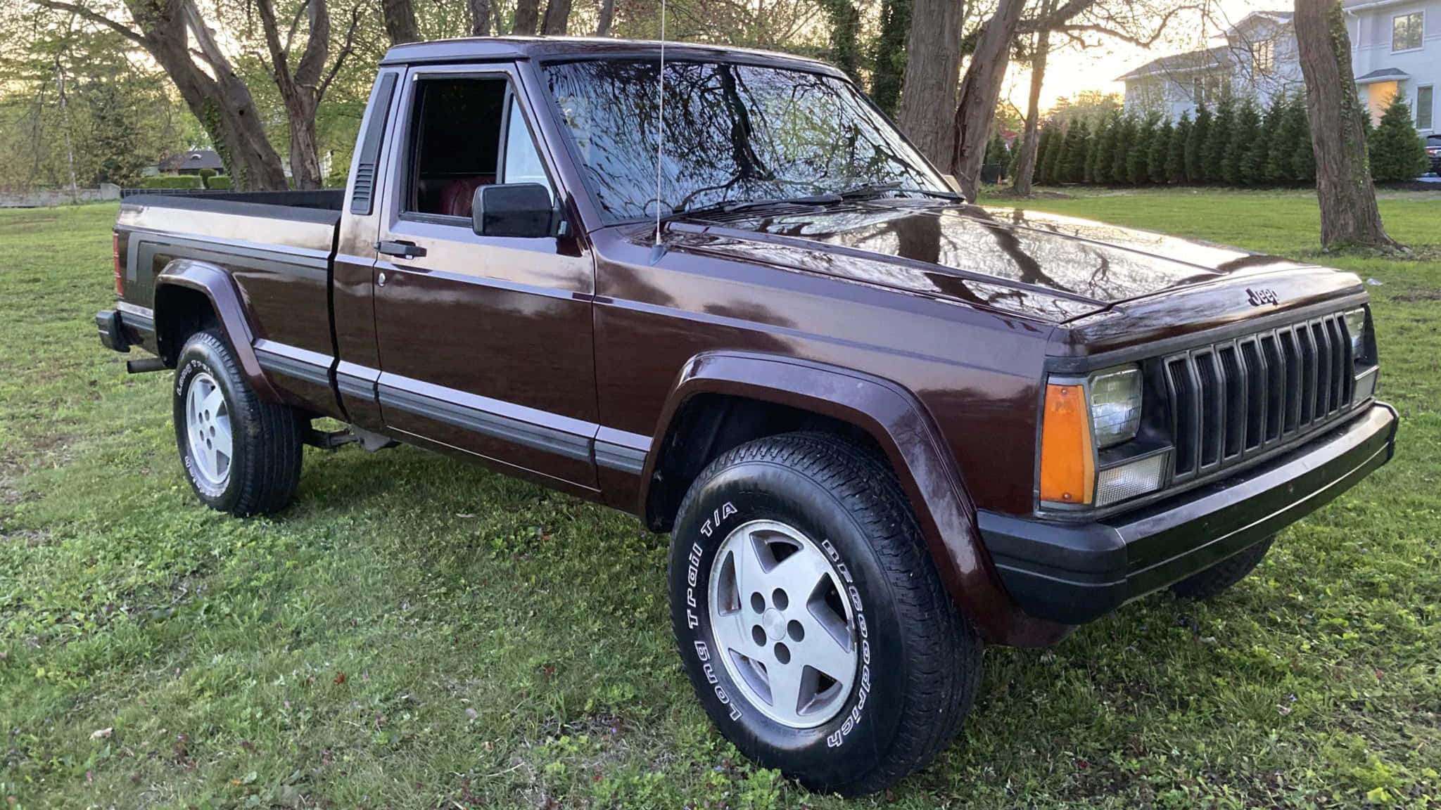 Jeep Comanche 桌布 壁紙 — 一輛栗色1980年代Jeep Cherokee皮卡車停在草地上，背景有樹木和房屋。