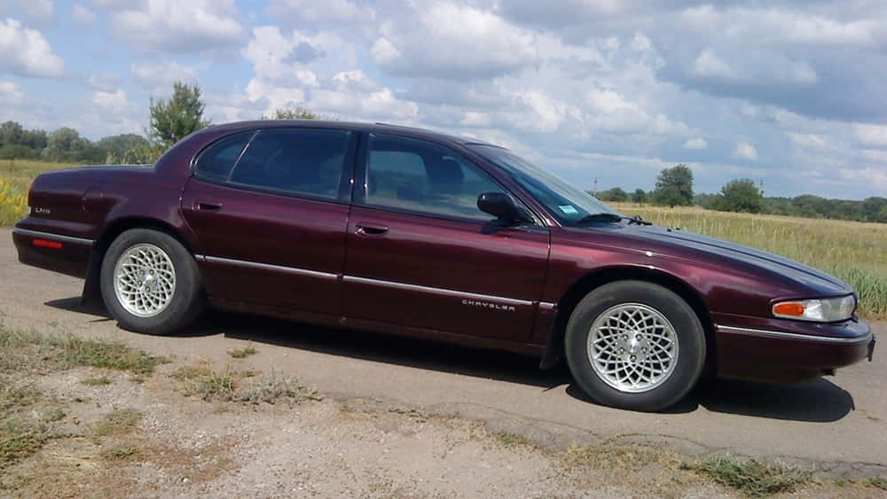 Chrysler Lhs 桌布 壁紙 — 一架栗色Chrysler LHS房車停泊在碎石路上，旁邊是草地，天空多雲。