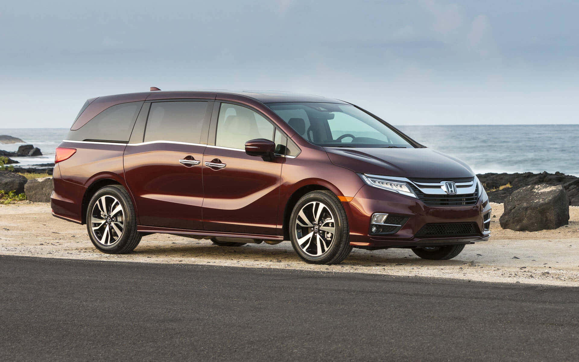 Honda Odyssey 桌布 壁紙 — 一架栗色本田Odyssey小型貨車停泊在沿海道路上，背景是海洋和岩石，天空多雲。