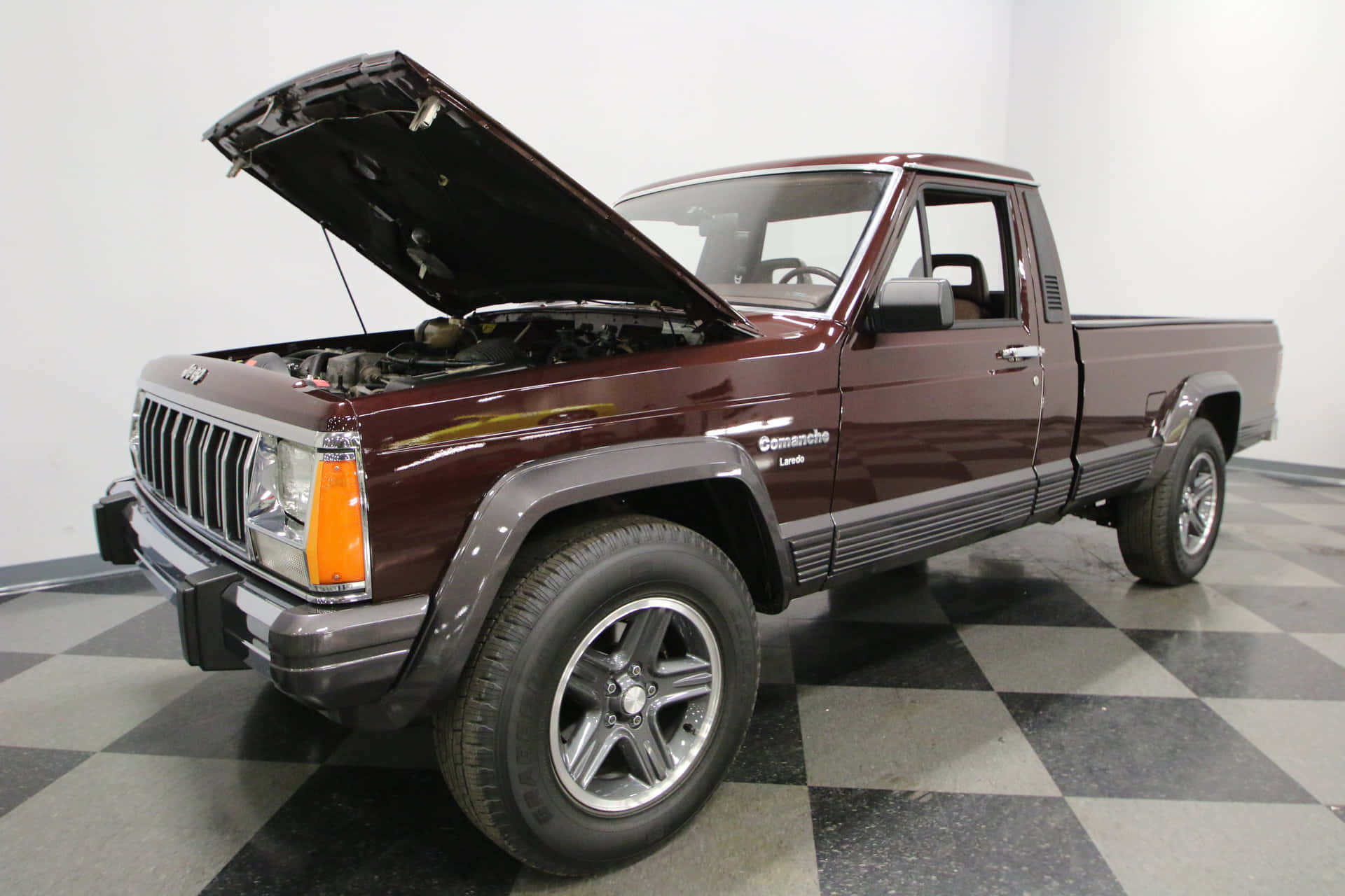 Jeep Comanche 桌布 壁紙 — 一架栗色Jeep Comanche皮卡車打開引擎蓋，停在明亮工作室的黑灰格子地板上。