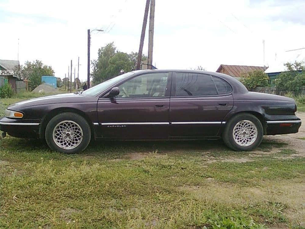 Chrysler Lhs 桌布 壁紙 — 一架栗色雪佛蘭房車停泊在草地上，背景有電線杆和房屋，天空多雲。