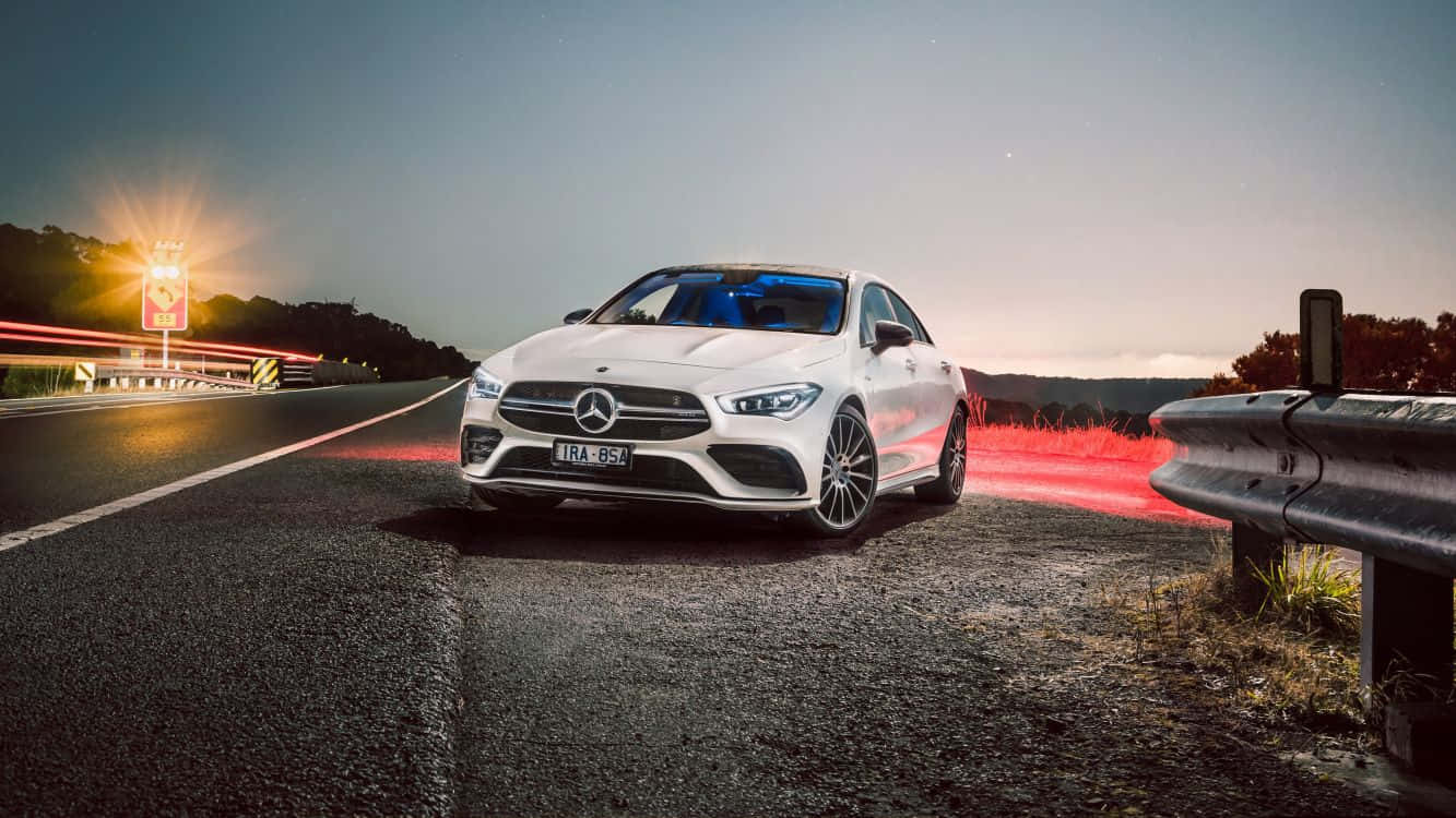 Mercedes Benz Cla-class 桌布 壁紙 — 一輛白色Mercedes-AMG CLA45 S在黃昏時停泊在路邊，背景有經過車輛的紅色光軌。