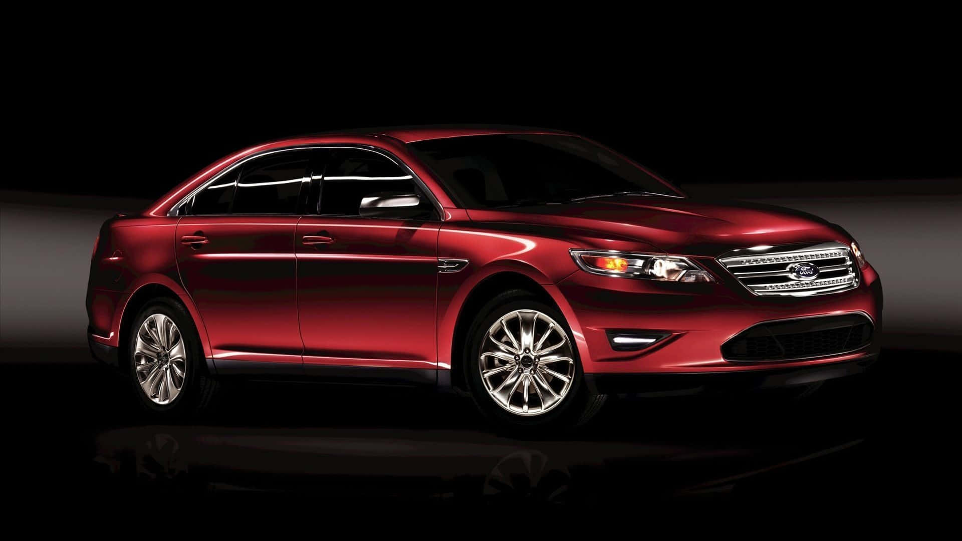 Ford Taurus 桌布 壁紙 — 一輛光澤的紅色轎車在黑色背景和反射地板的攝影棚燈光下閃耀。