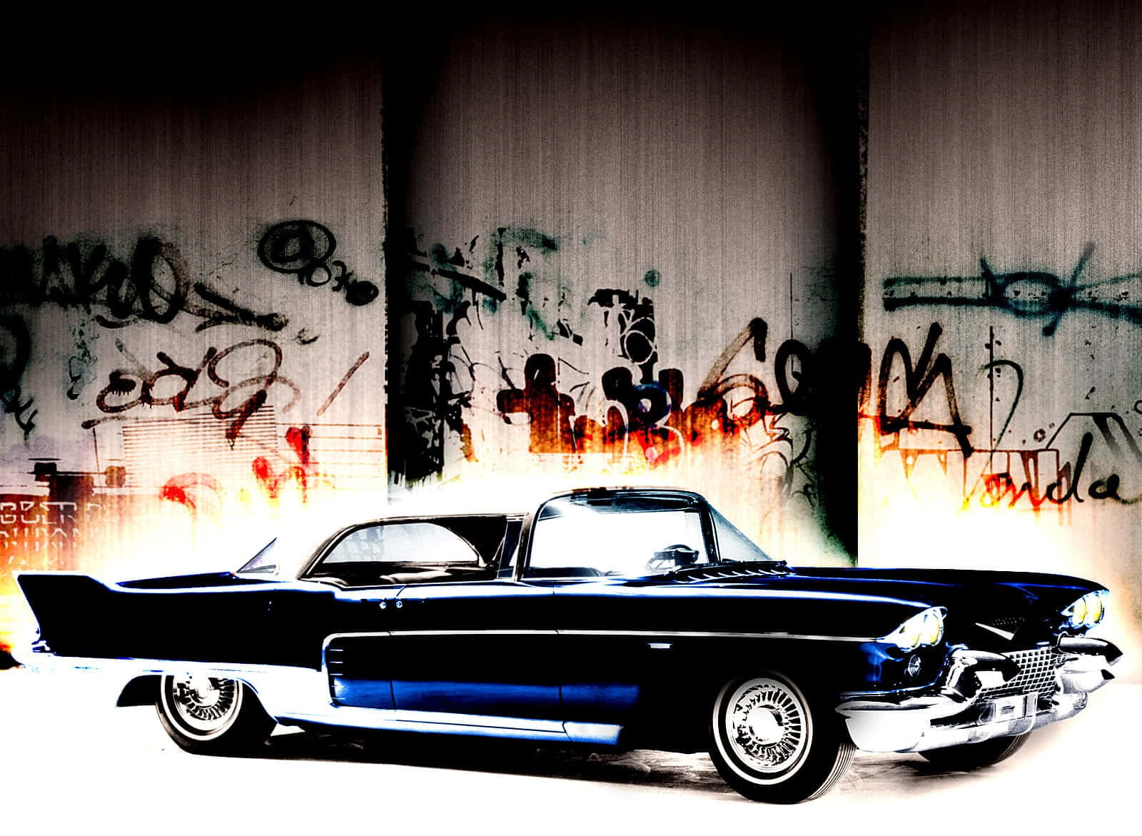 Cadillac Eldorado 桌布 壁紙 — 一輛亮黑色經典汽車在強光下閃耀，背景是佈滿塗鴉的都市牆壁，帶有火熱的橙色點綴。