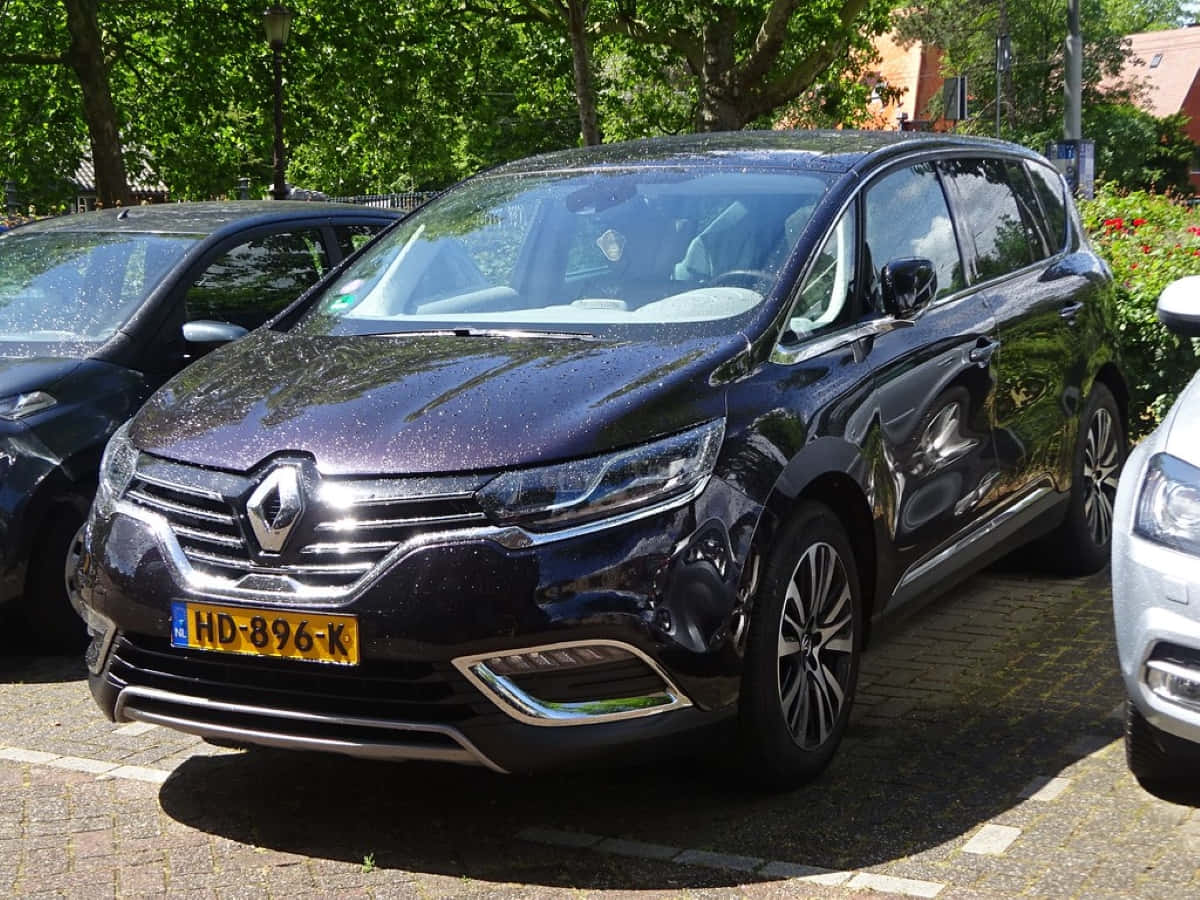 Renault Espace 桌布 壁紙 — 一輛亮黑色雷諾Espace停泊在陽光明媚的磚地停車場，附近有樹木和其他車輛。